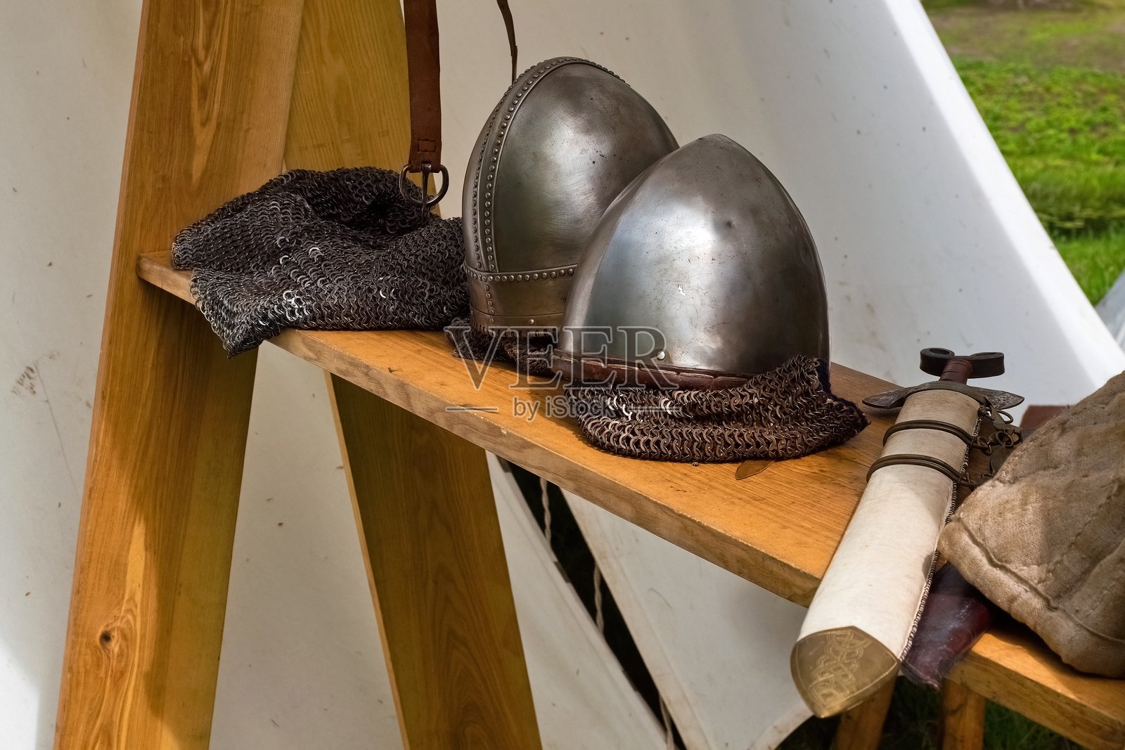户外展示中世纪盔甲和武器。重现装备，包括斧头和头盔。维京风格的装备在中世纪博览会上。照片摄影图片