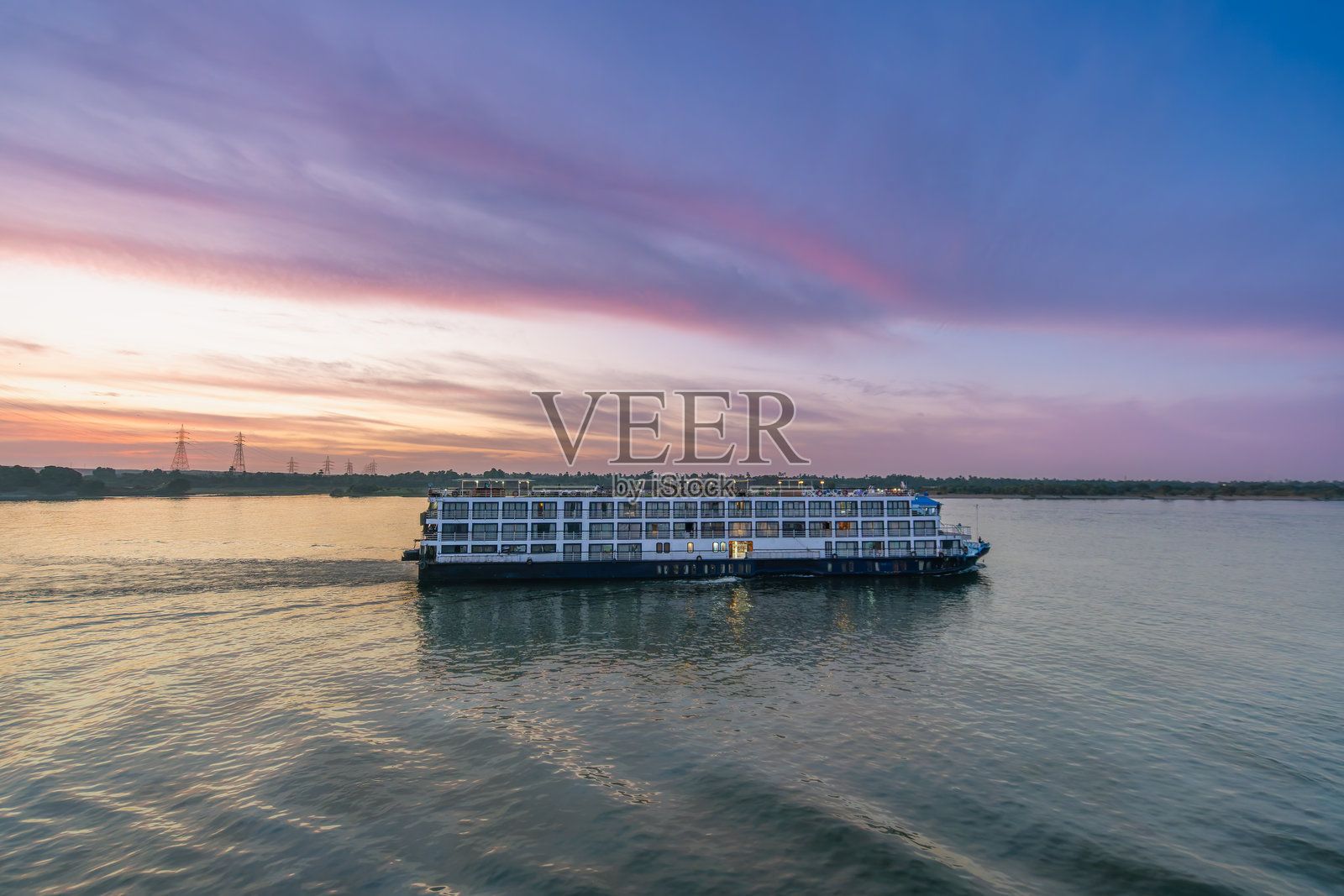 尼罗河游船在埃及阿斯旺的埃斯纳水闸经过日落时分。照片摄影图片