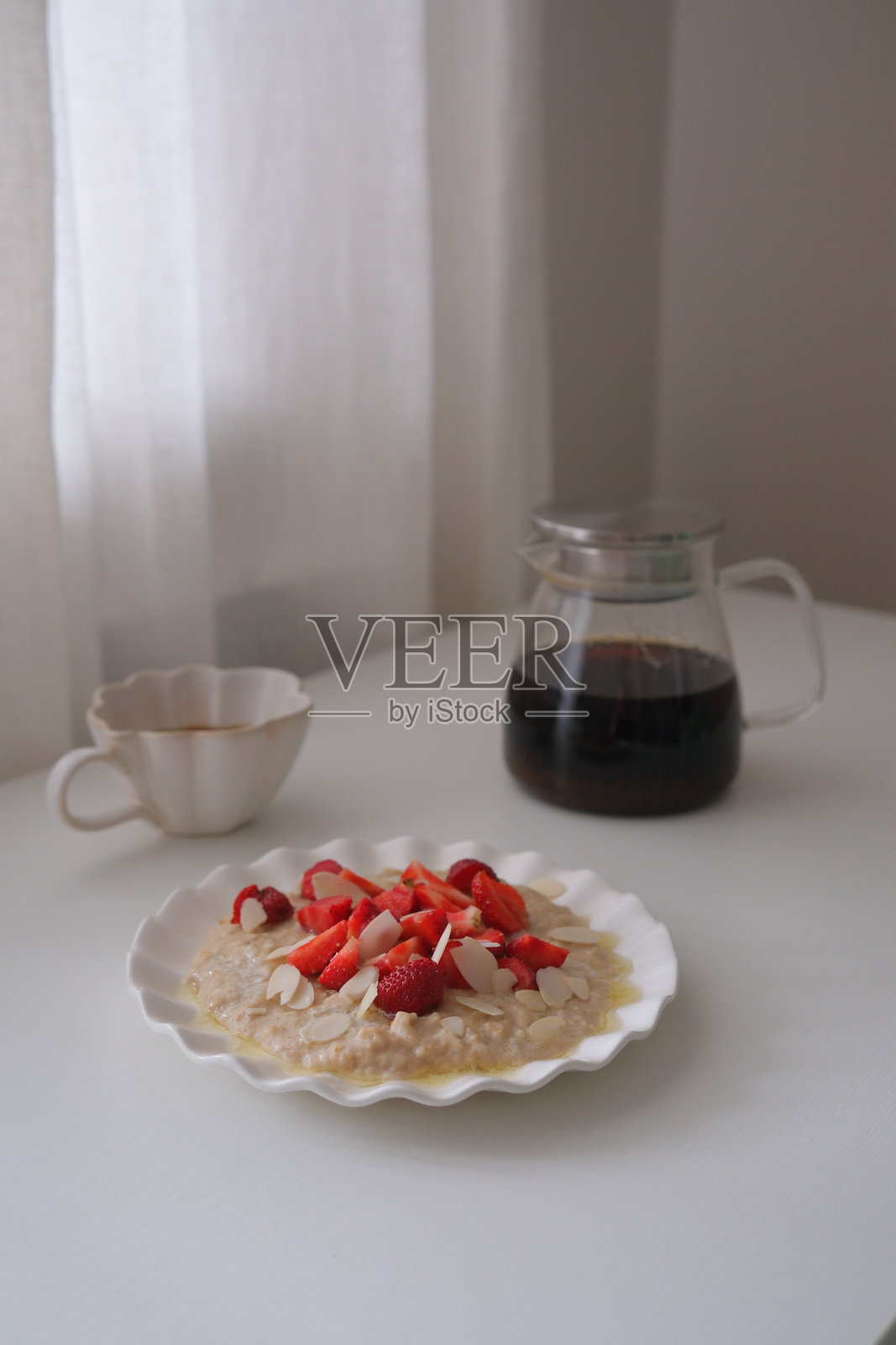 宁静的早餐场景，碗里盛着草莓燕麦粥，旁边是一杯冒着热气的咖啡。照片摄影图片