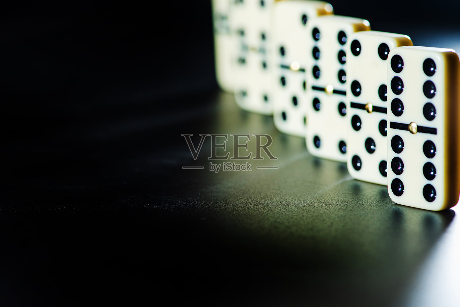 多米诺骨牌，美丽的白色骨牌小心地放置在黑色表面上，选择性对焦。照片摄影图片