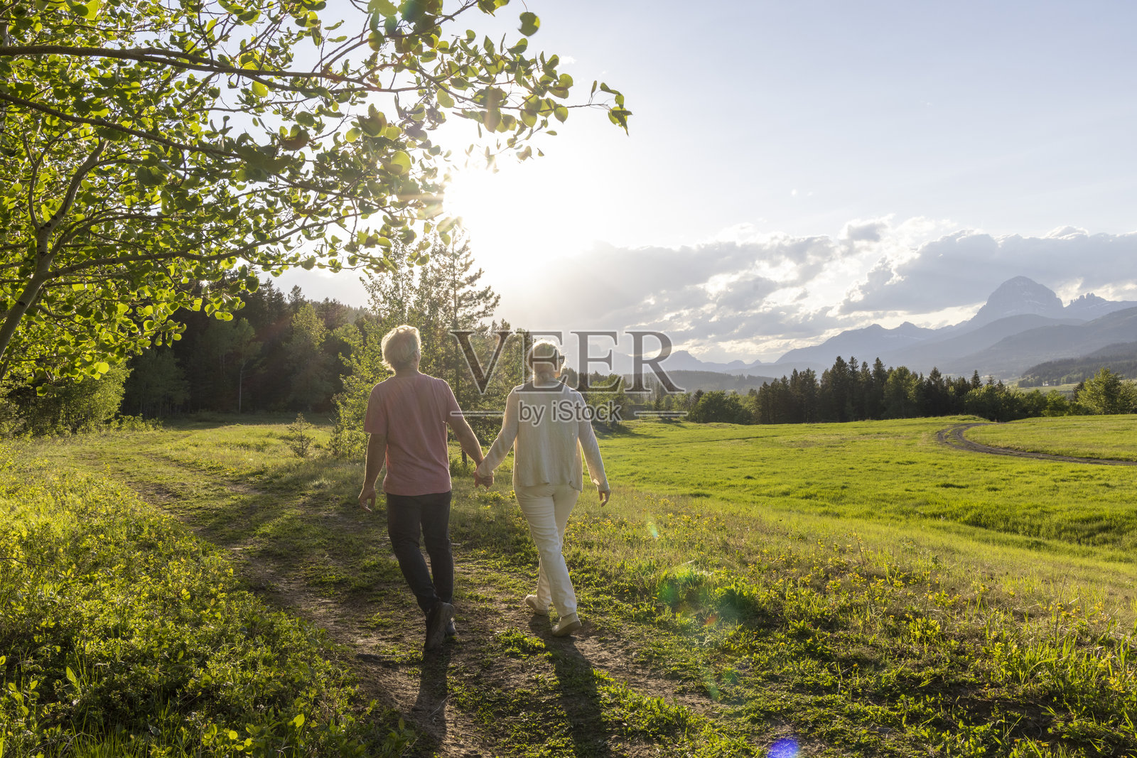 成熟夫妇在日落时分漫步于山间草甸照片摄影图片