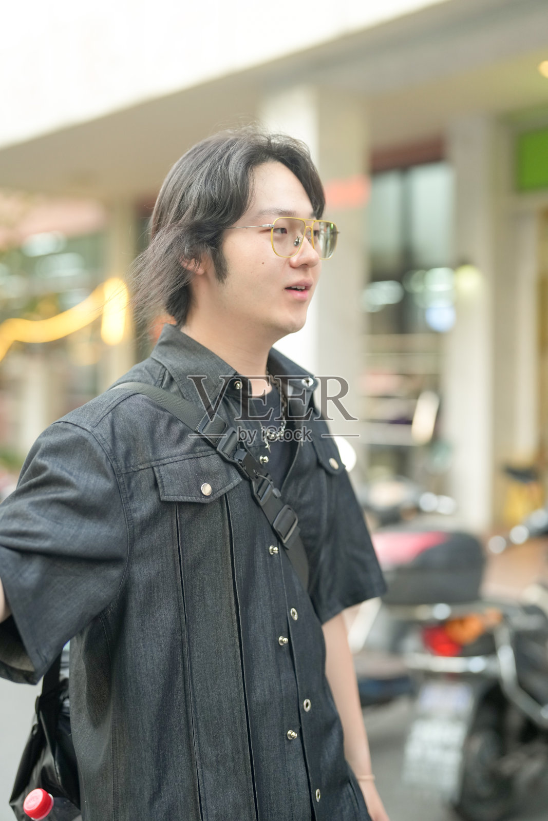 一位20多岁的中国男子，戴着眼镜，在阳光明媚的春天走过上海徐汇区的大学校园。宁静、平和的场景充满了阳光和新鲜的绿意。照片摄影图片