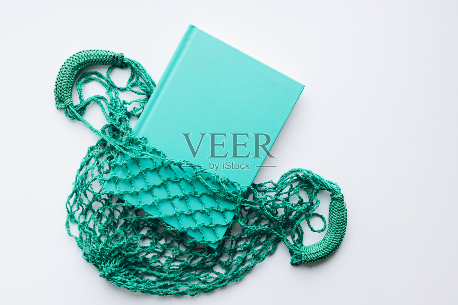 白色背景上的绿色网袋中的书籍，纸张回收和环保概念。照片摄影图片