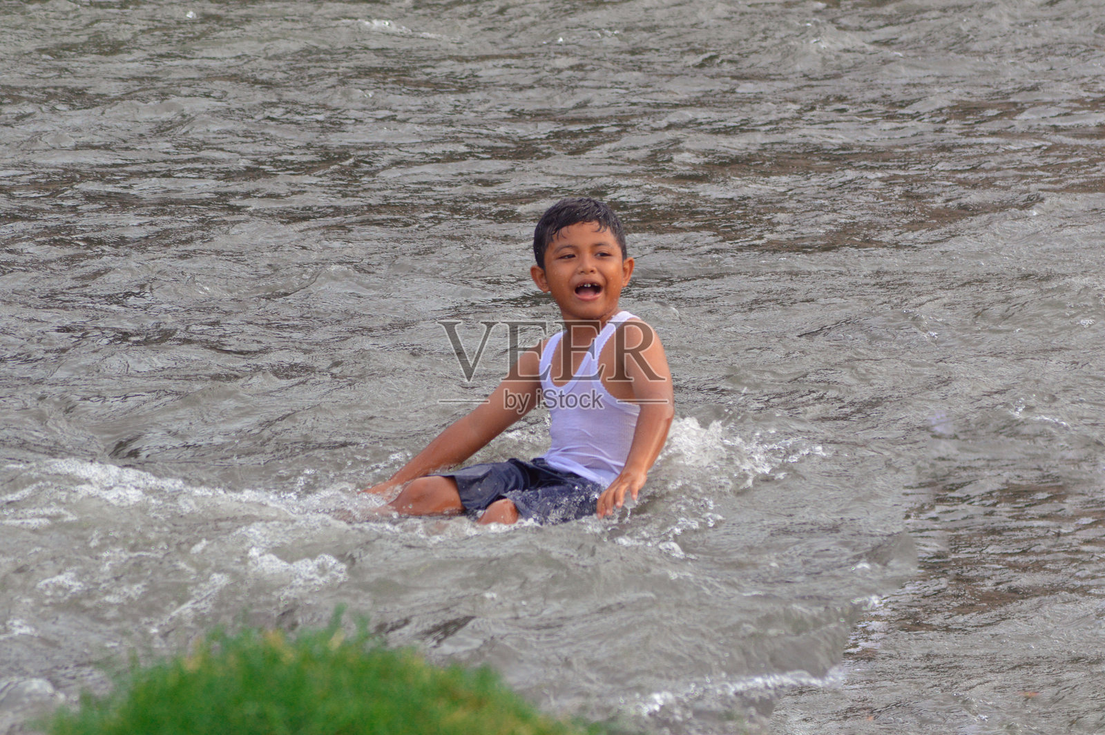 男孩在河流中独自放松，伸展双腿。照片摄影图片