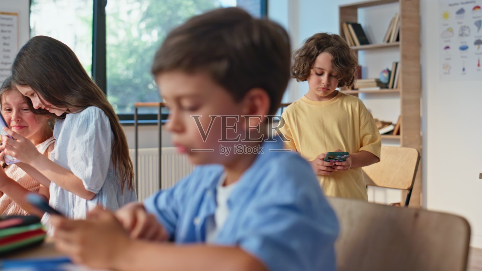 专注的男学生在课堂上使用智能手机特写。学校里的孩子们照片摄影图片