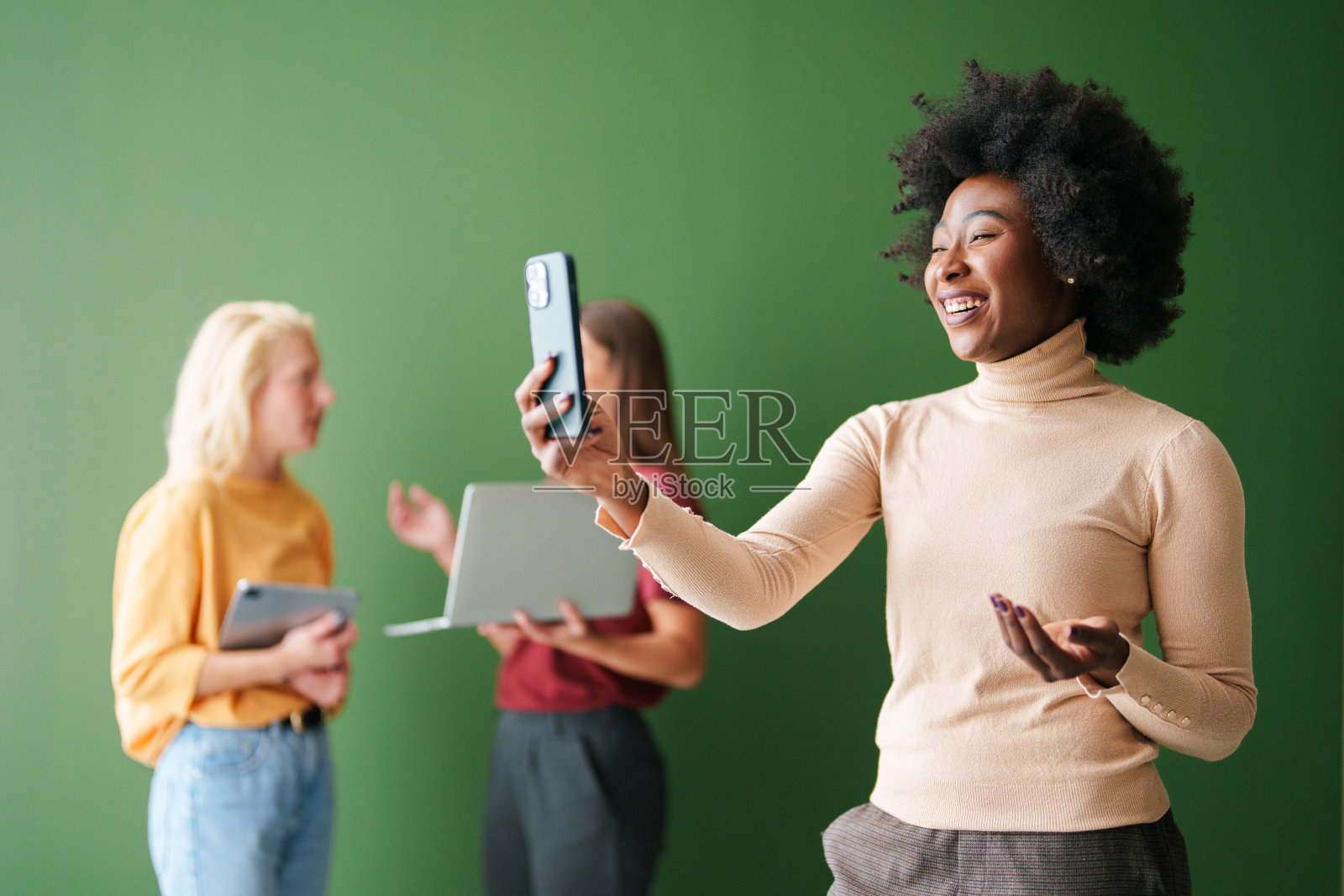 多元化的年轻人使用科技，聚焦于微笑的女性，光线明亮照片摄影图片