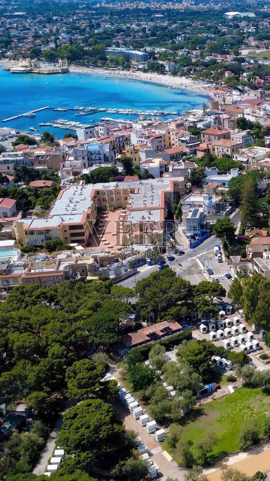 夏季海边生机勃勃的小镇海岸景观，碧蓝的海水和郁郁葱葱的绿树照片摄影图片