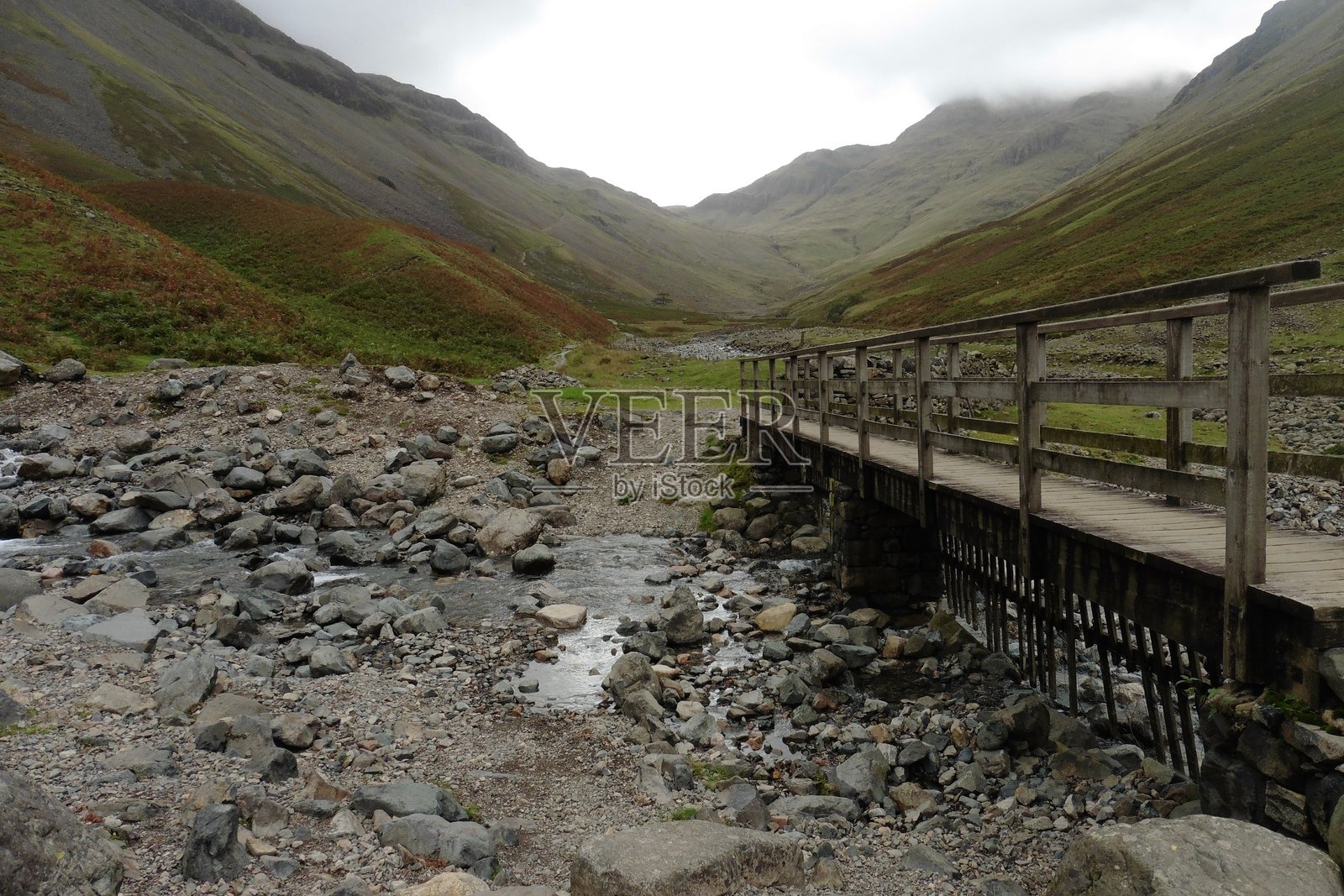湖区国家公园干涸河床上的人行天桥，背后是山脉天际线照片摄影图片