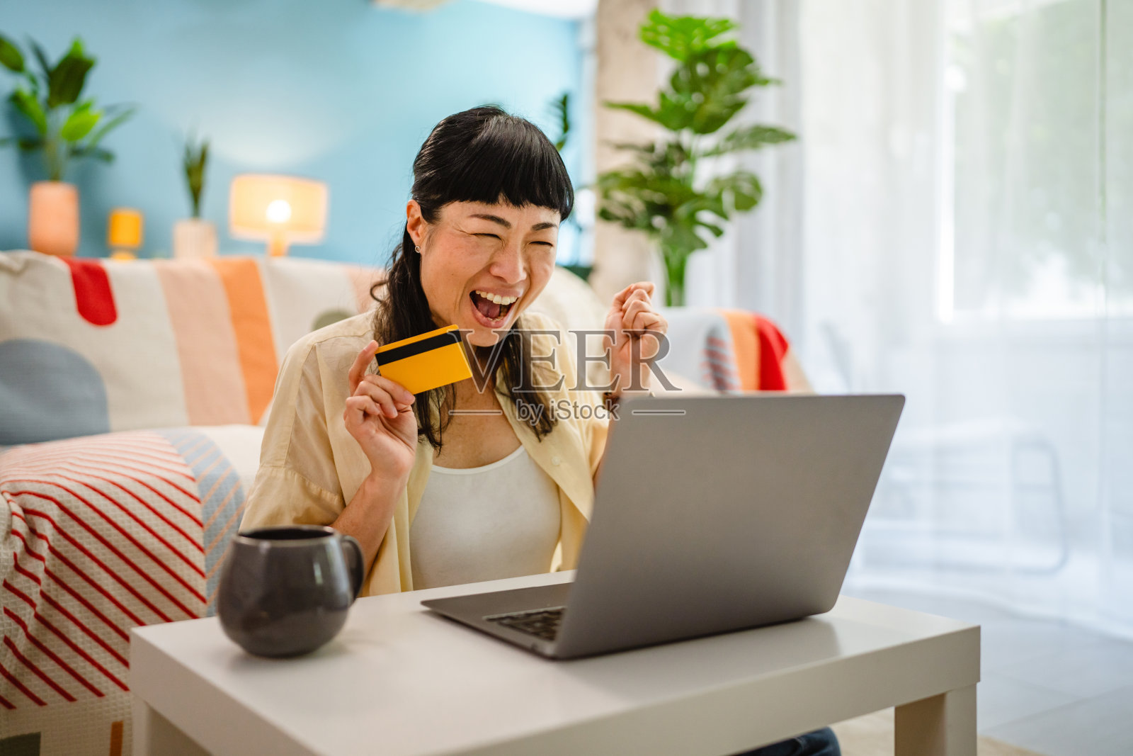 快乐的日本女性在家中通过笔记本电脑在线购物照片摄影图片
