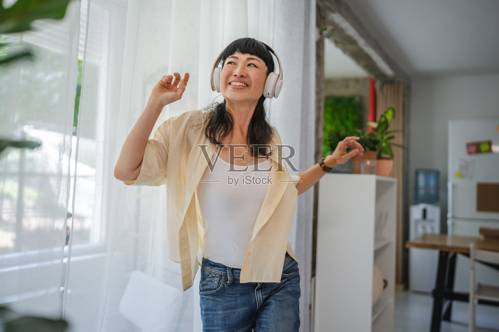 活泼的日本女性在家中戴着耳机听音乐并跳舞照片摄影图片