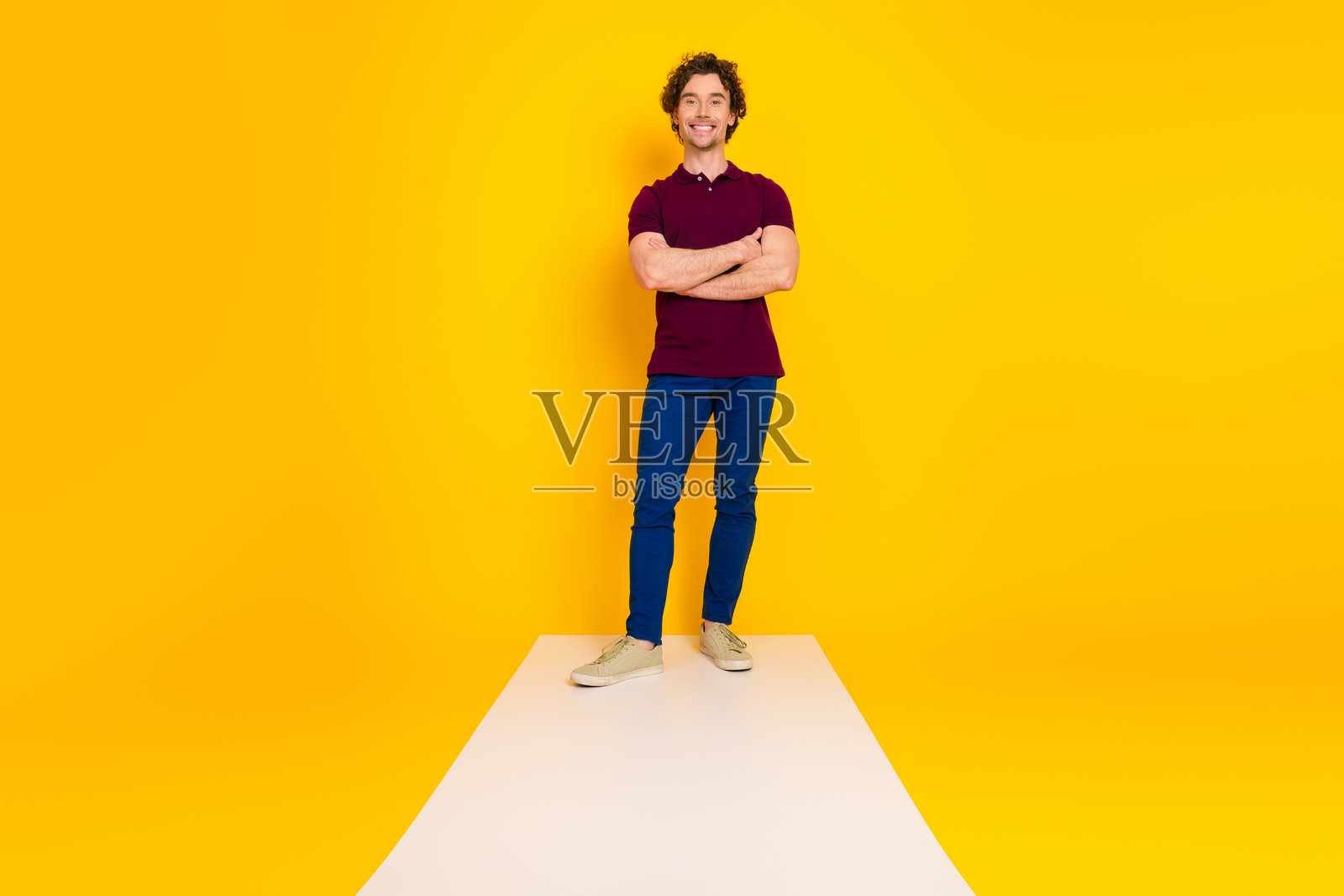 自信的年轻男子穿着酒红色的 polo 衫，站在充满活力的黄色背景前，散发出时尚气息。照片摄影图片