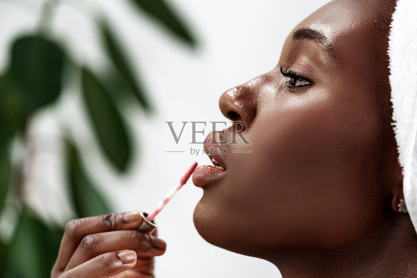 女性在明亮现代的环境中进行美容程序时涂抹唇彩照片摄影图片