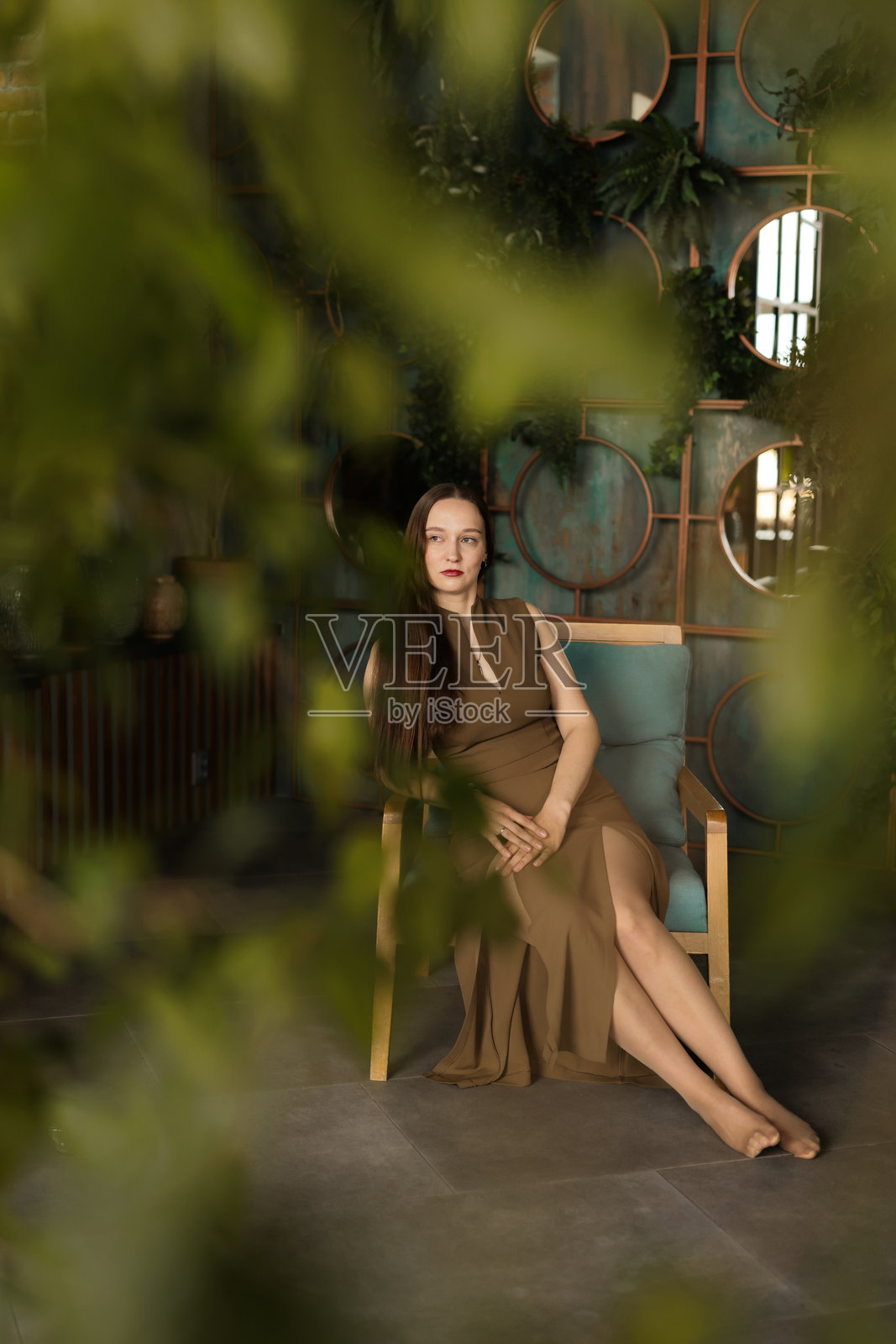 一位优雅的女性在装饰有美丽绿植和植物的时尚室内摆姿势照片摄影图片