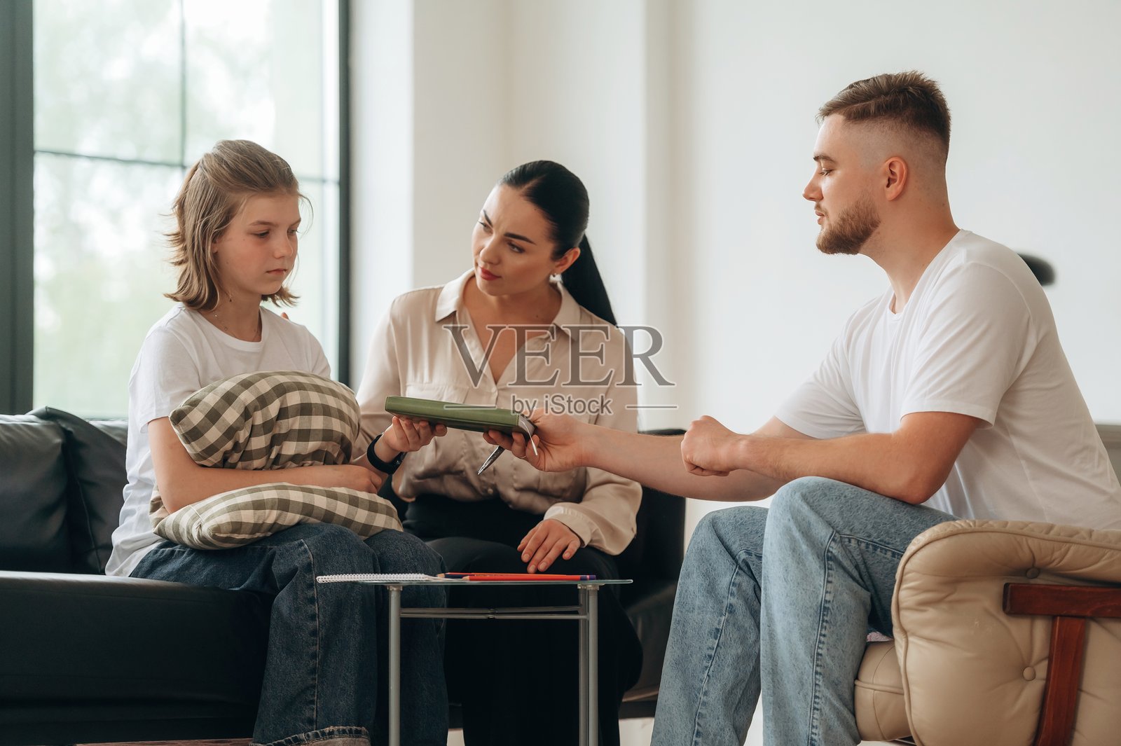 男医生正在帮助。母亲和女儿正在心理医生的预约中。照片摄影图片