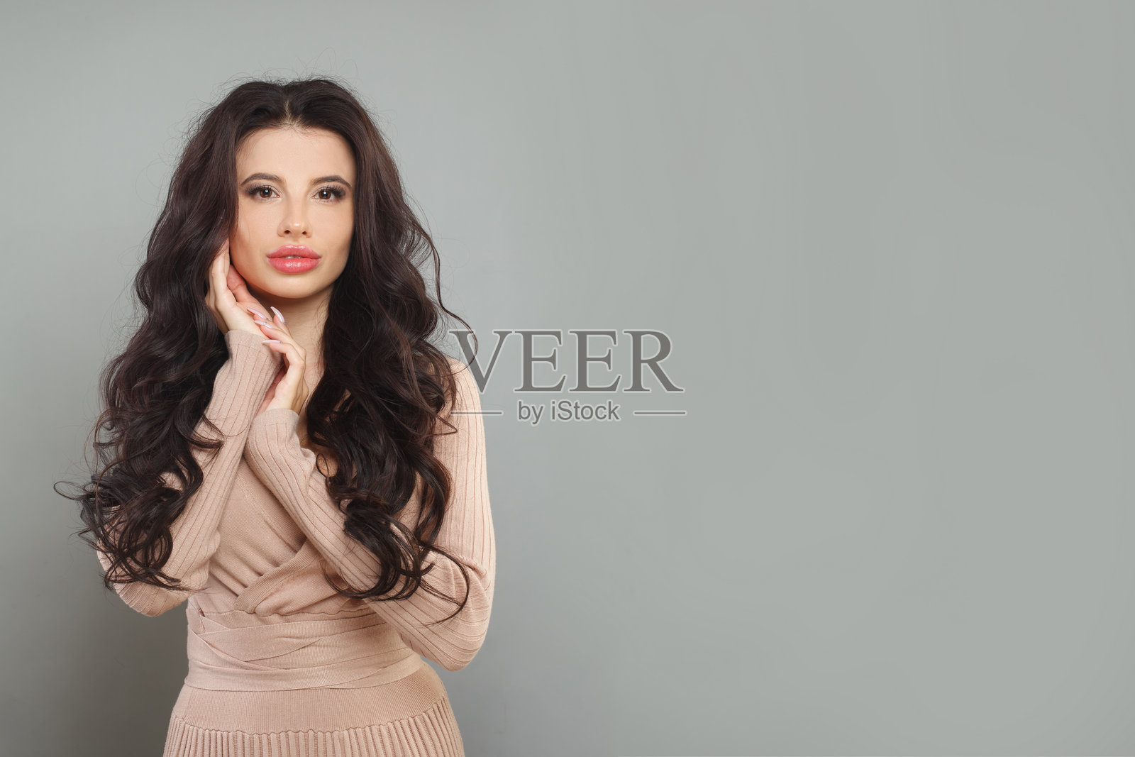 棕发模特女性在灰色背景上摆姿势，时尚肖像照片摄影图片