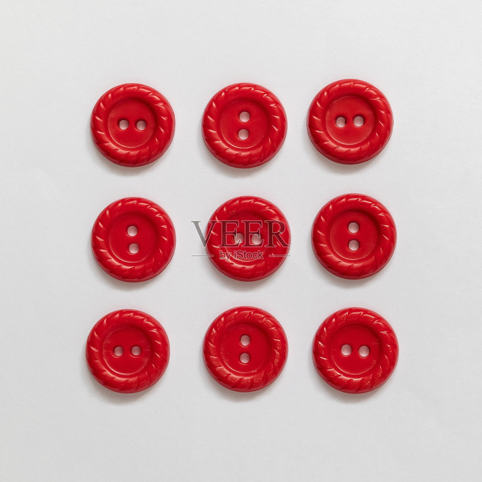 一组红色塑料纽扣，背景为白色。缝纫工具。俯视图。照片摄影图片