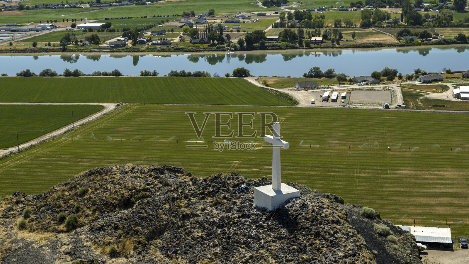 岩石纪念碑下的河边农业。基督教十字架俯瞰着爱达荷州马辛的农田和水域。照片摄影图片