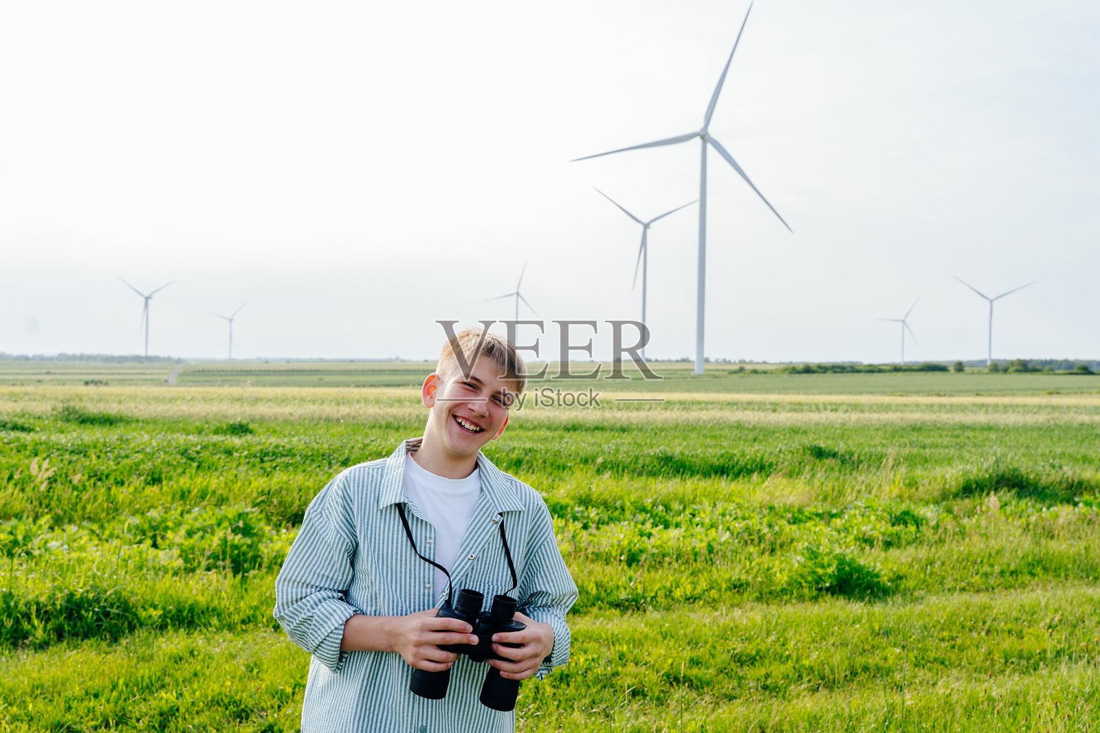 乡村风景中，少年男孩在风力发电机附近看地图照片摄影图片
