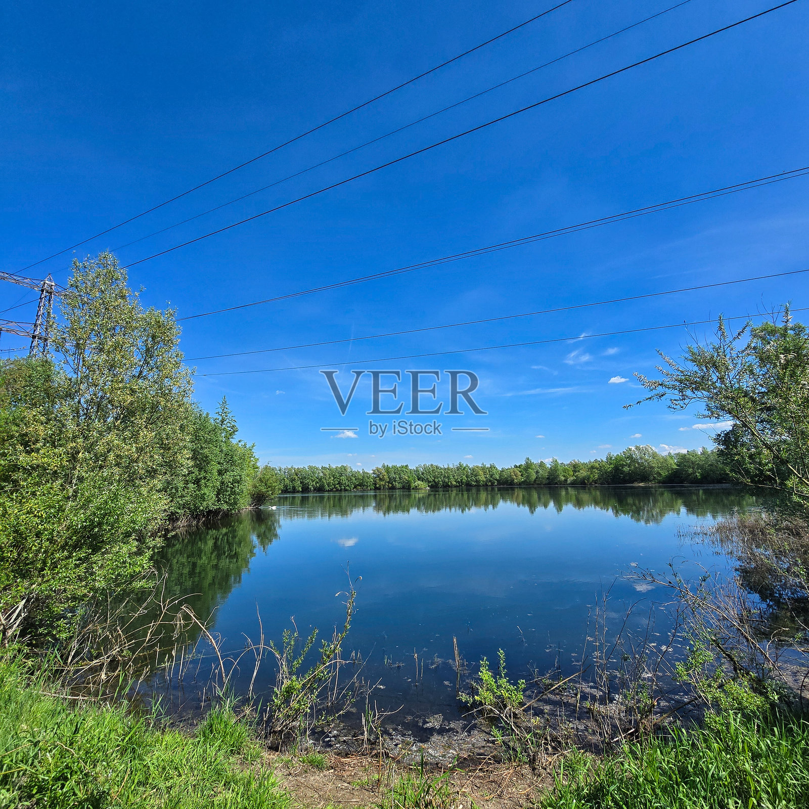 在晴朗的蓝天下，宁静的湖面上反射出平和的景象，科尔丁格湖，汉诺威，帕滕森照片摄影图片