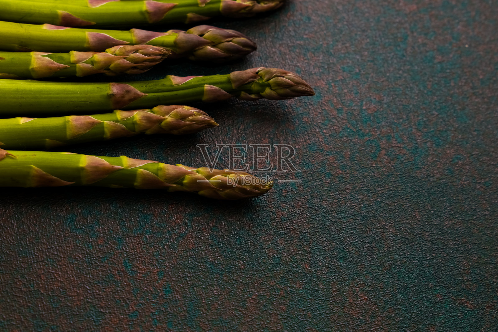 新鲜的芦笋整齐地摆放在有纹理的表面上，准备烹饪或装饰菜肴。照片摄影图片