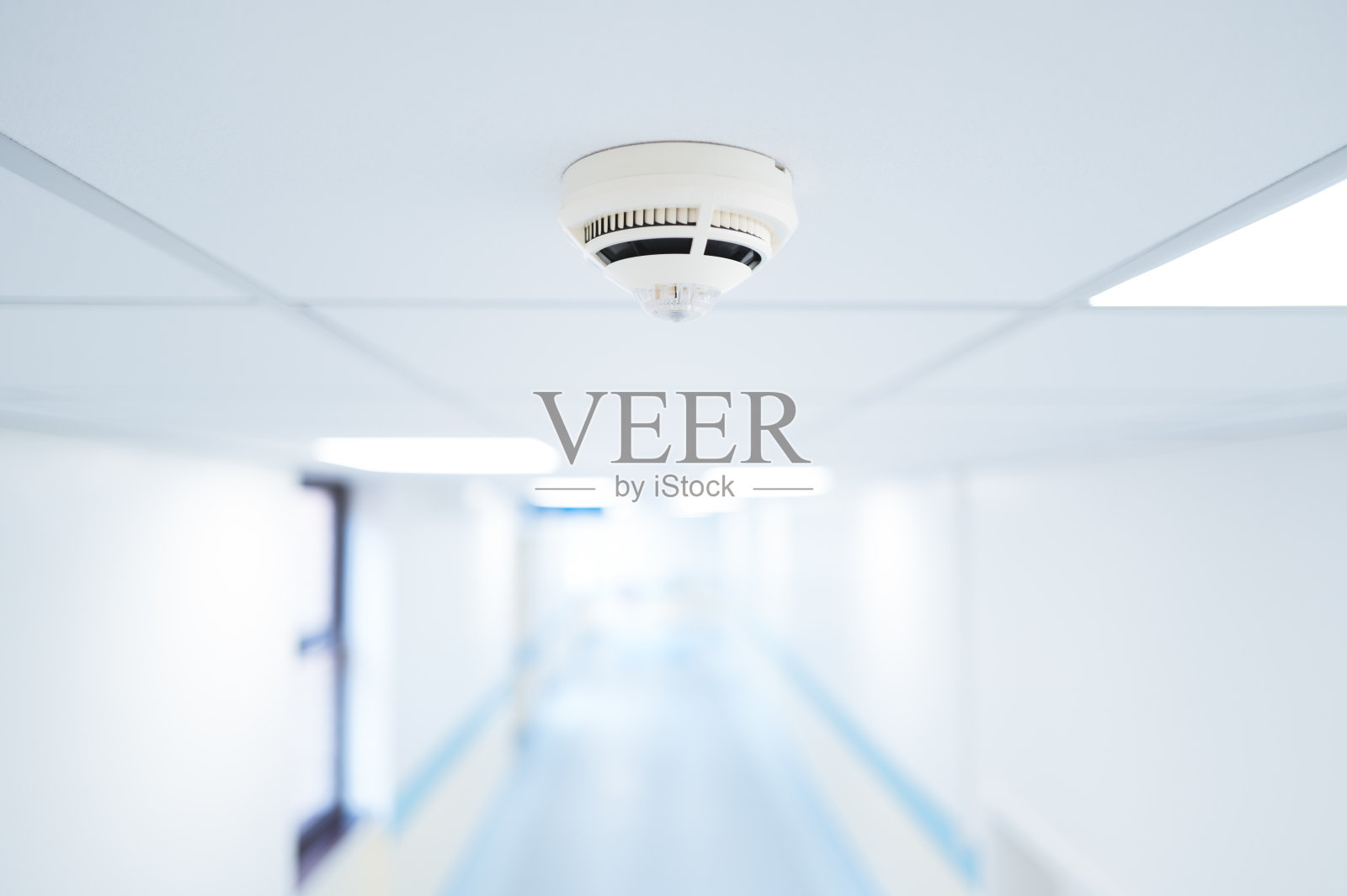 在英国一所典型的NHS医院的天花板上，可以看到烟雾探测器的浅焦点。照片摄影图片
