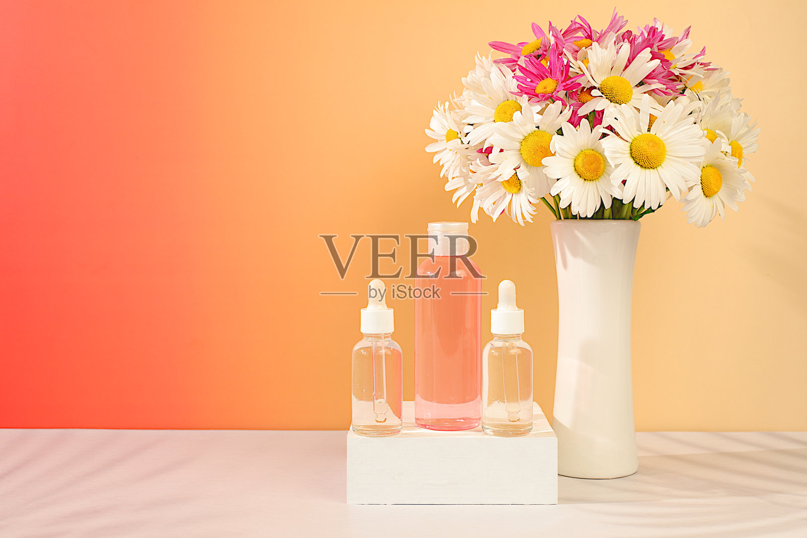 美容水与新鲜花卉（如花园洋甘菊和木槿）的健康组合，水疗沙龙广告卡，自然自我护理与健康生活方式概念，花卉的抽象组合照片摄影图片