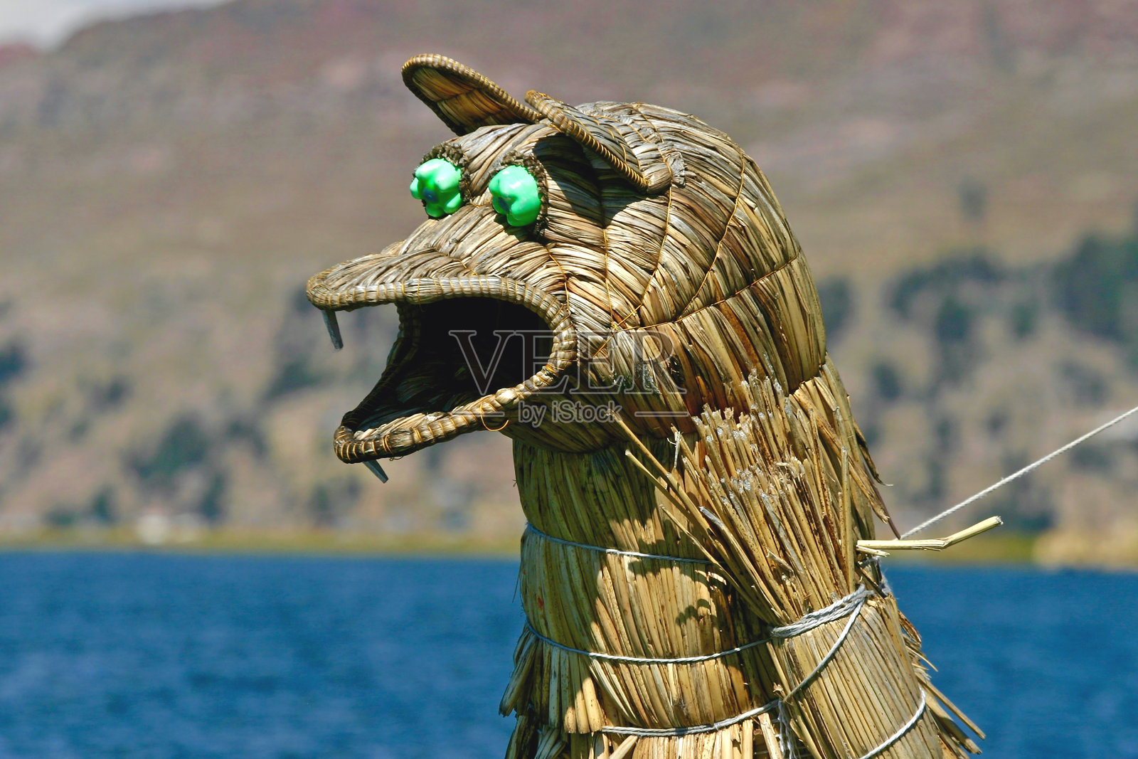 在秘鲁的的的喀喀湖上，一艘传统芦苇船的船头上有一个雕像，眼睛用塑料瓶的瓶口制作。照片摄影图片