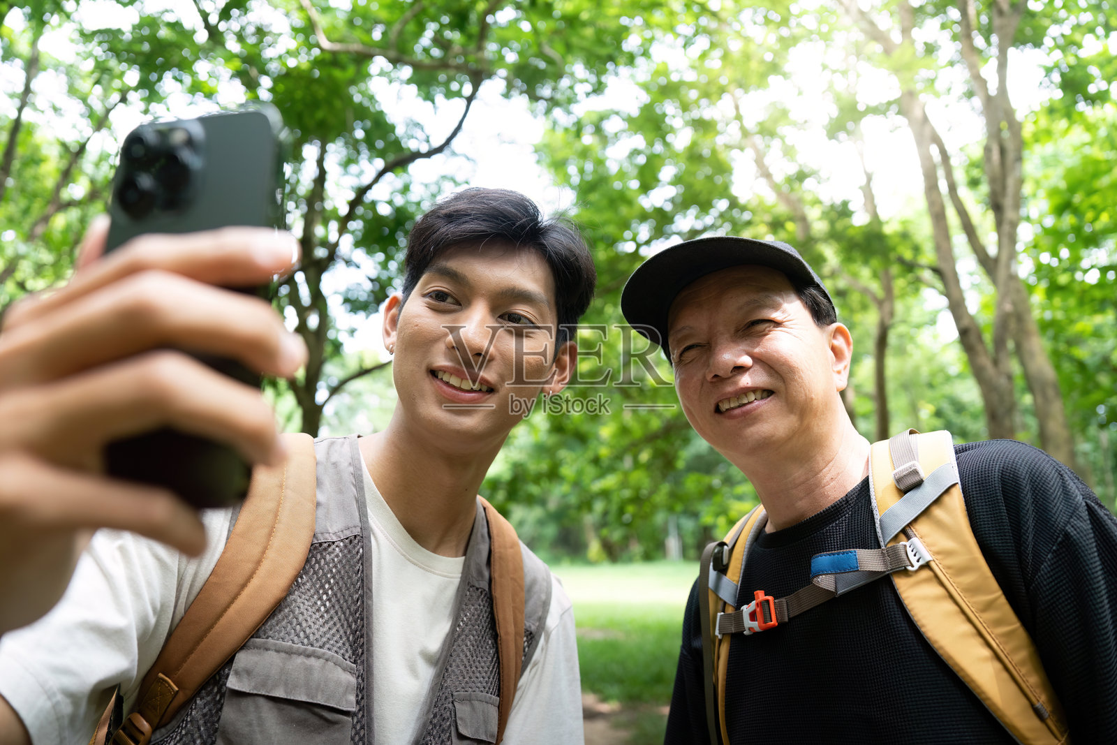 父亲和儿子一起享受大自然。在公园里拍摄自拍，捕捉快乐的瞬间。照片摄影图片