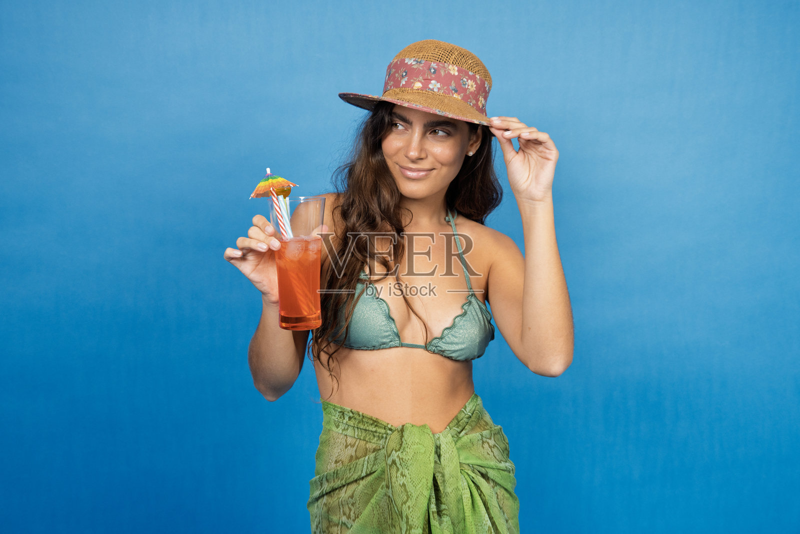 年轻女性穿着夏季服装，手持鸡尾酒，面带微笑照片摄影图片