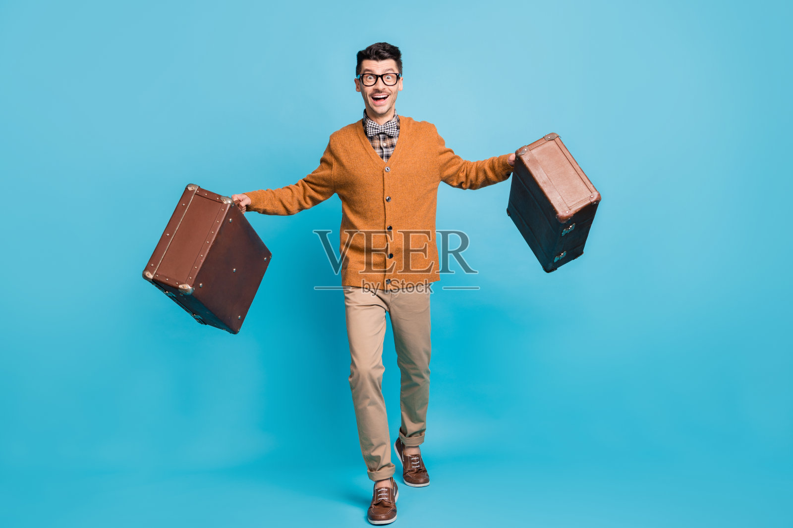 全身照，快乐兴奋的棕发男士手持行李箱，旅行度假，背景为蓝色。照片摄影图片