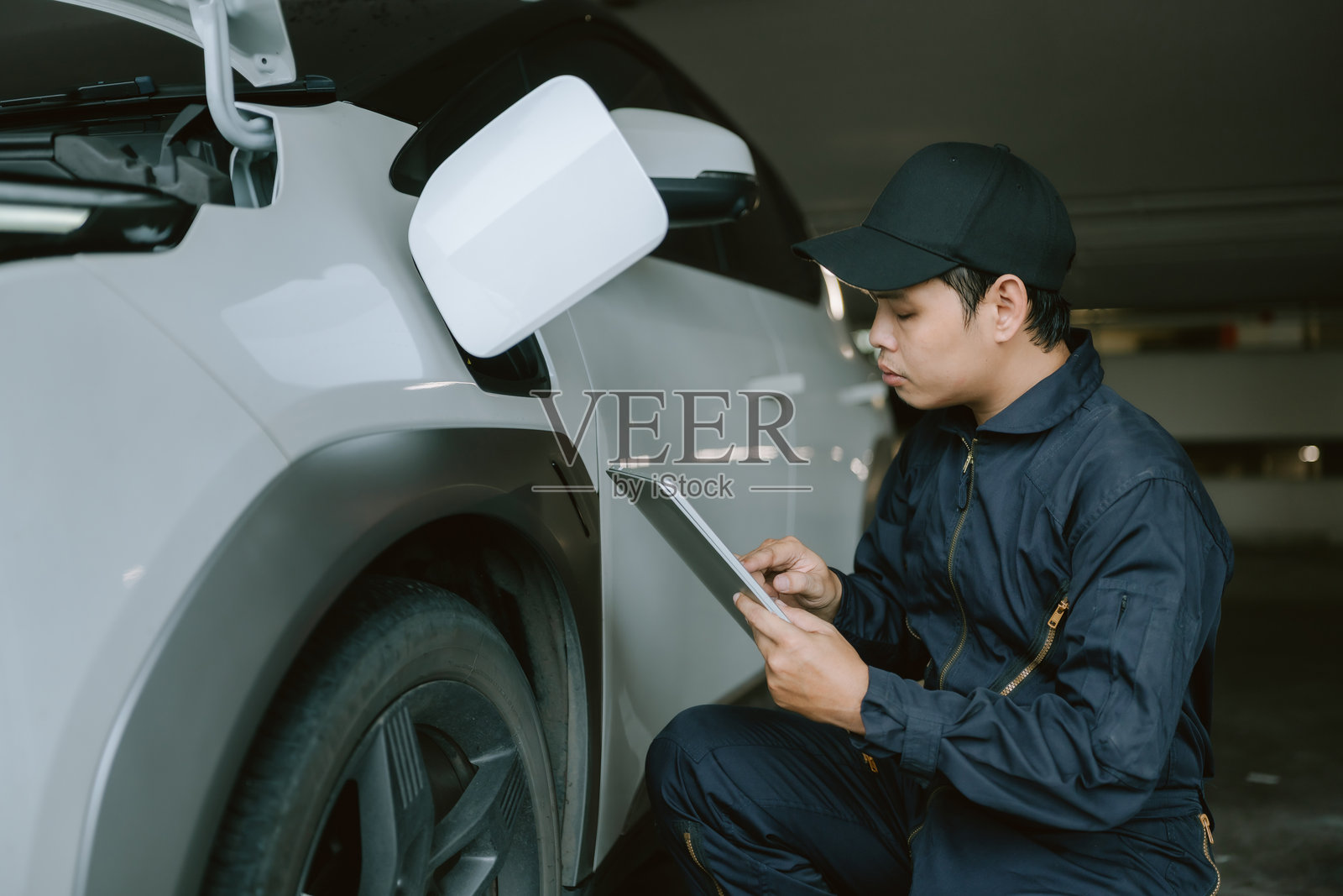 机械师在地下车库的日光下使用诊断工具检查车辆照片摄影图片