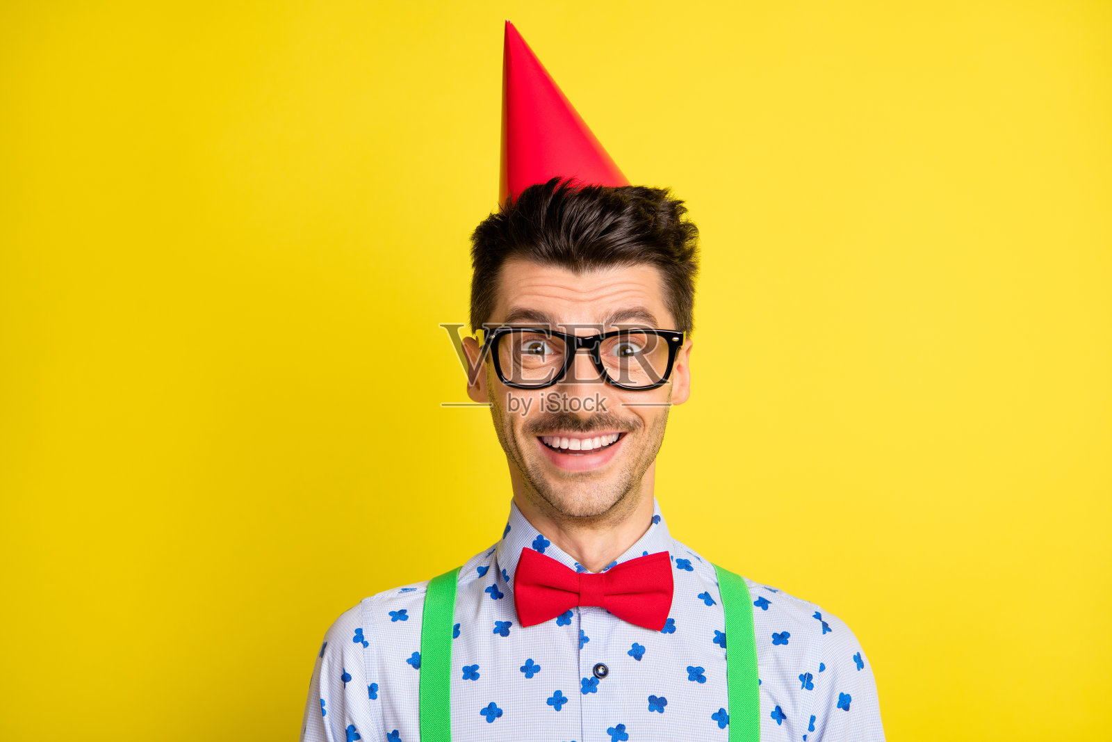 穿着节日帽子的迷人幽默快乐男士肖像，背景为明亮的黄色。照片摄影图片