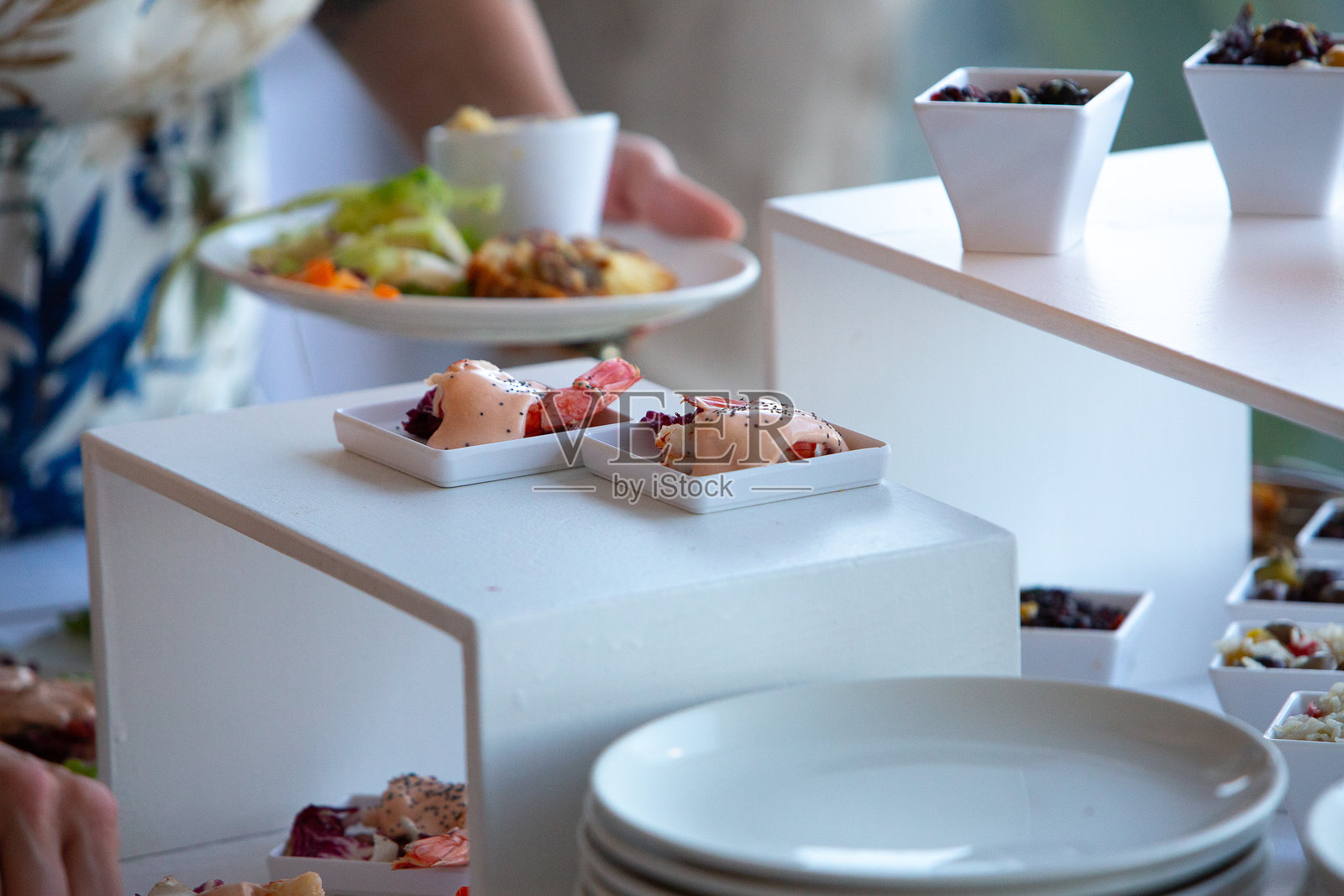 餐饮服务员在活动的自助餐桌上放置食物盘照片摄影图片