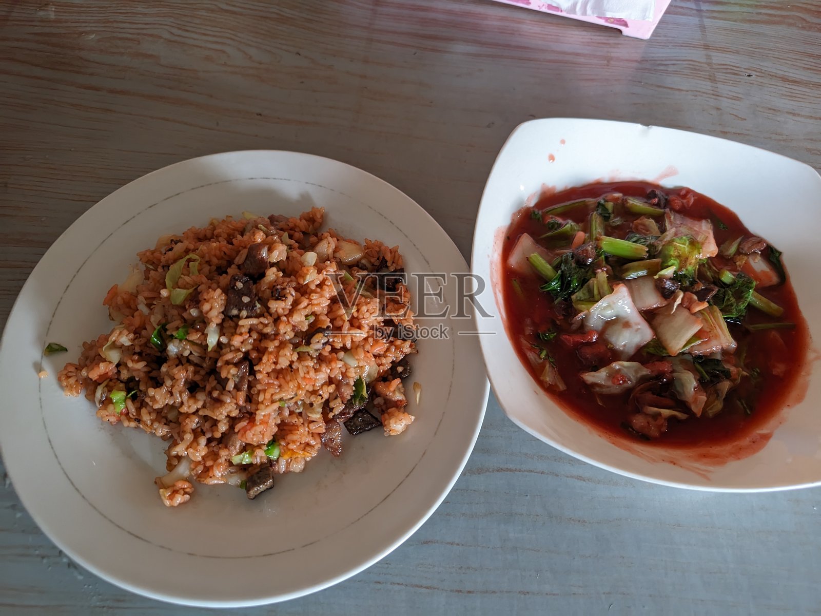 白盘子上的炒饭和蔬菜，称为卡普蔡，放在桌子上。照片摄影图片