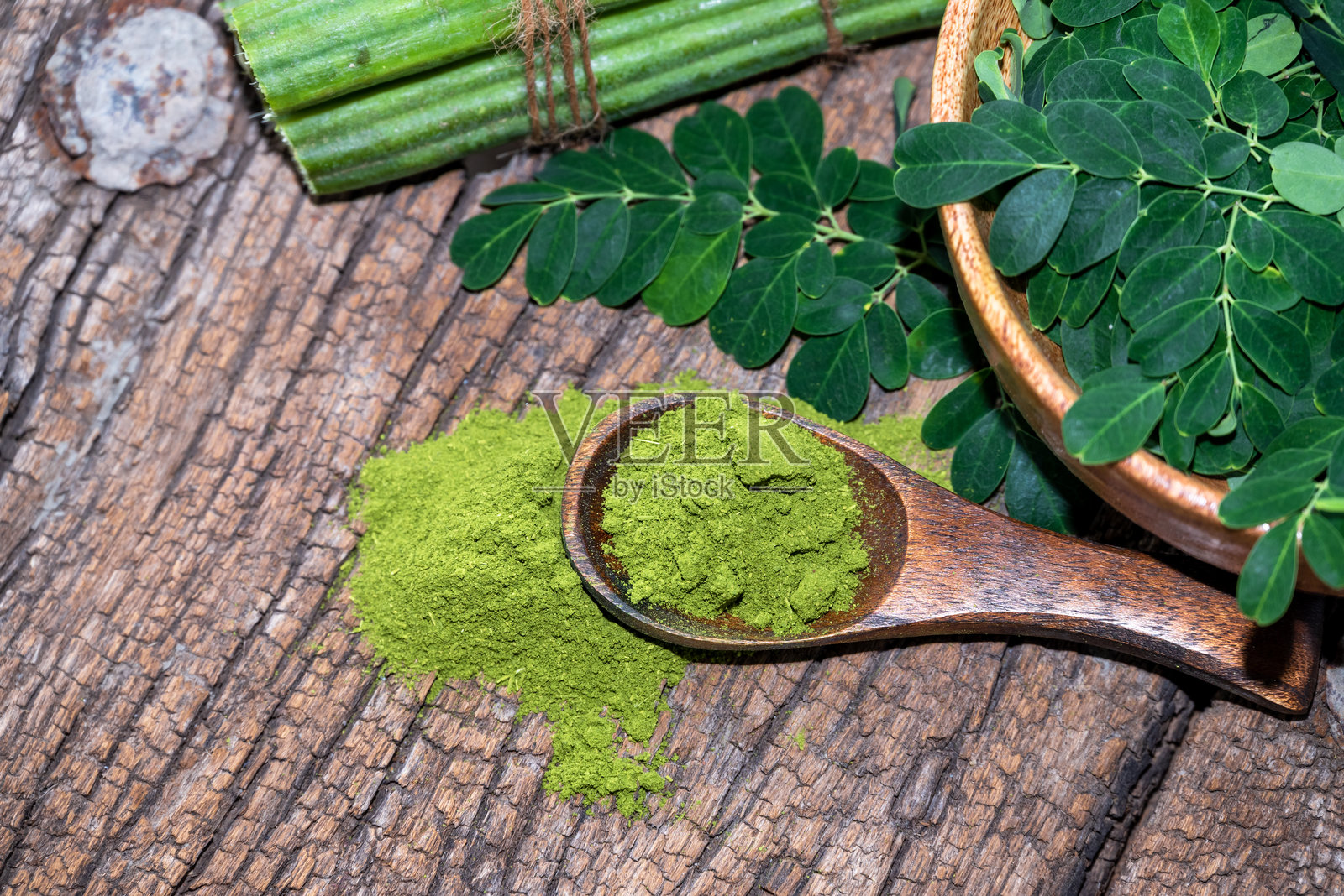 木碗中的辣木叶与木质背景上的辣木粉照片摄影图片