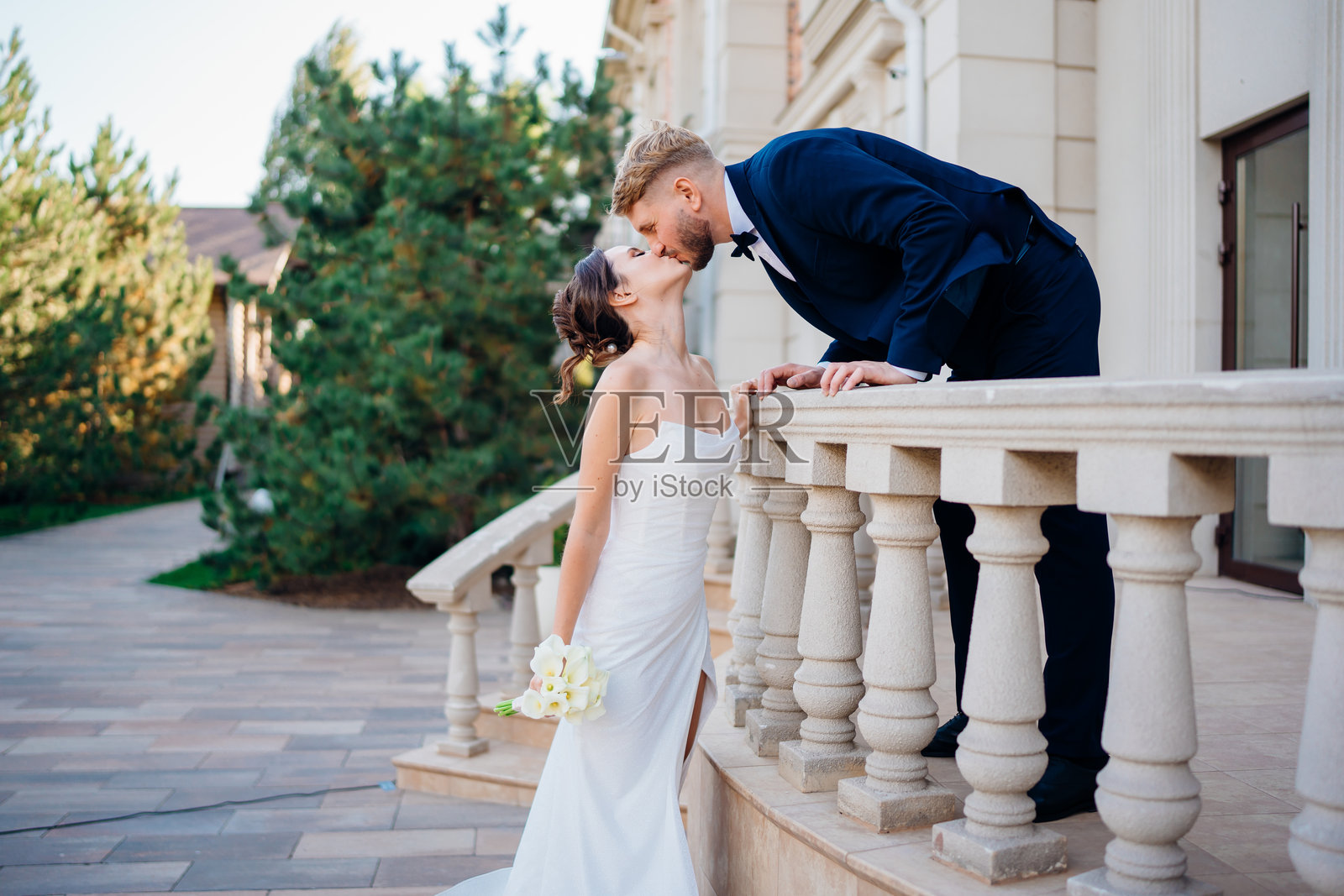 幸福而相爱的新人在入口处的阳台栏杆上。照片摄影图片