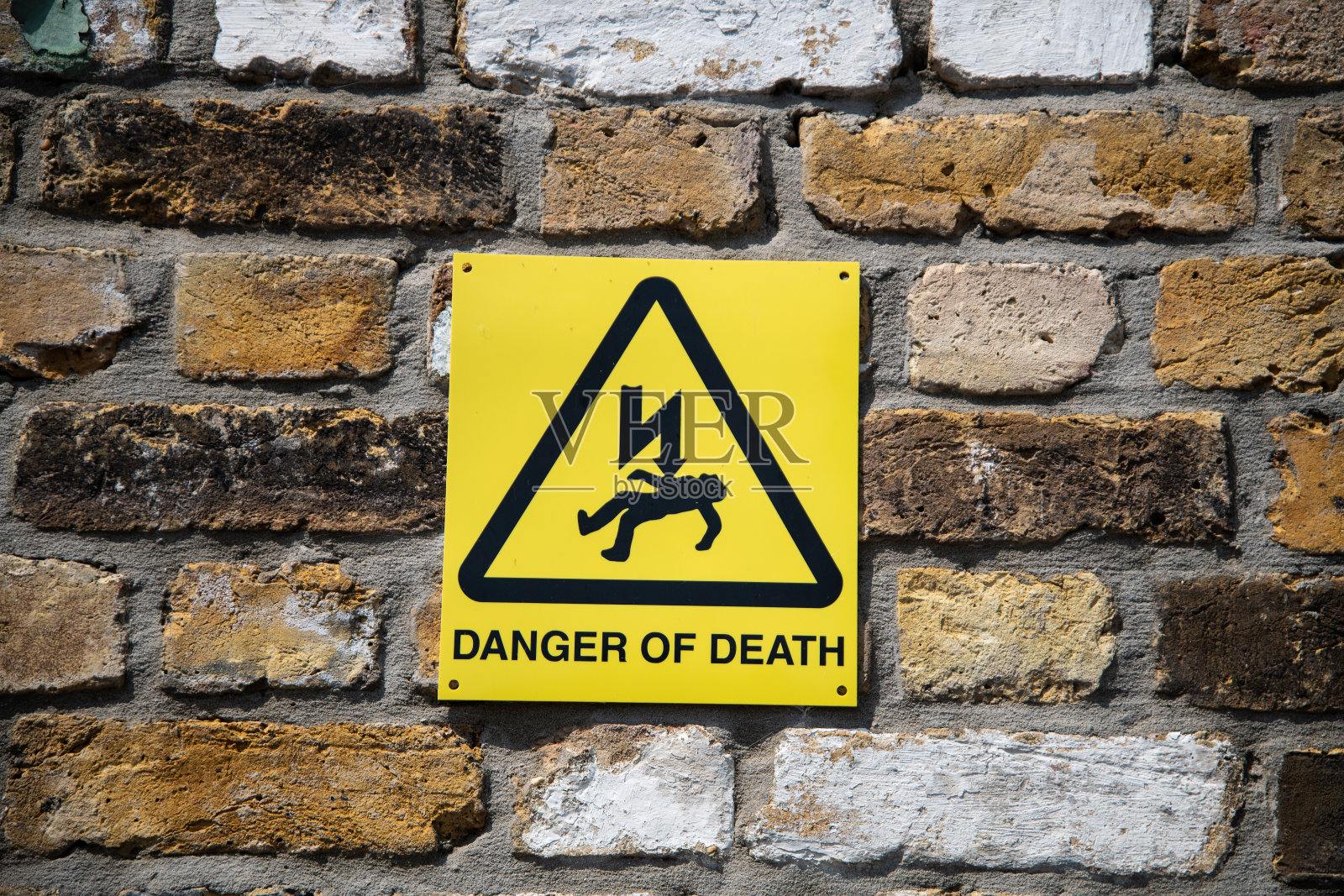 黄色死亡危险警告标志，带有闪电和坠落人物符号，典型的英国安全标识。照片摄影图片