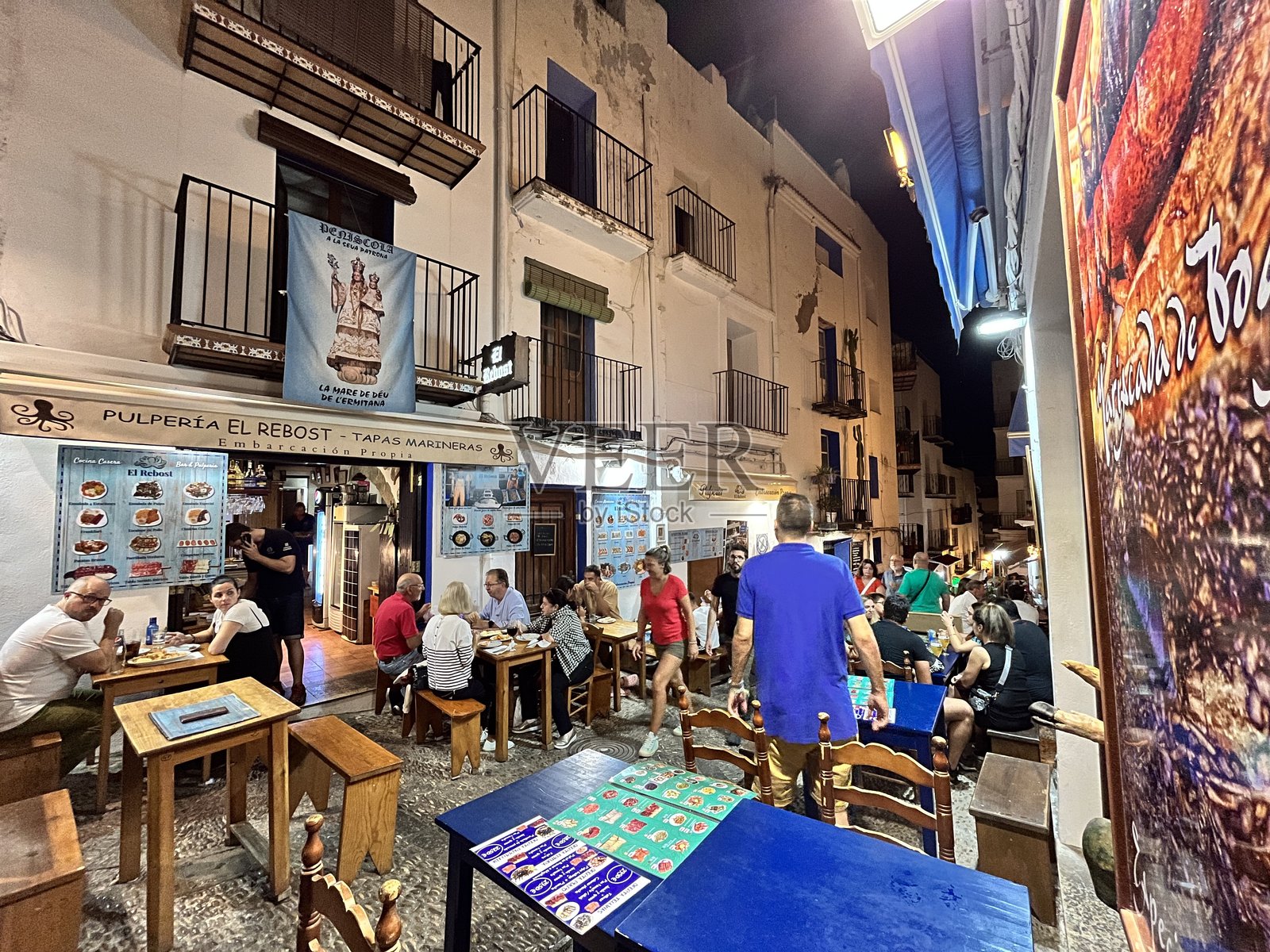 游客们在西班牙佩尼斯科拉的户外餐厅享受夜晚的用餐时光照片摄影图片