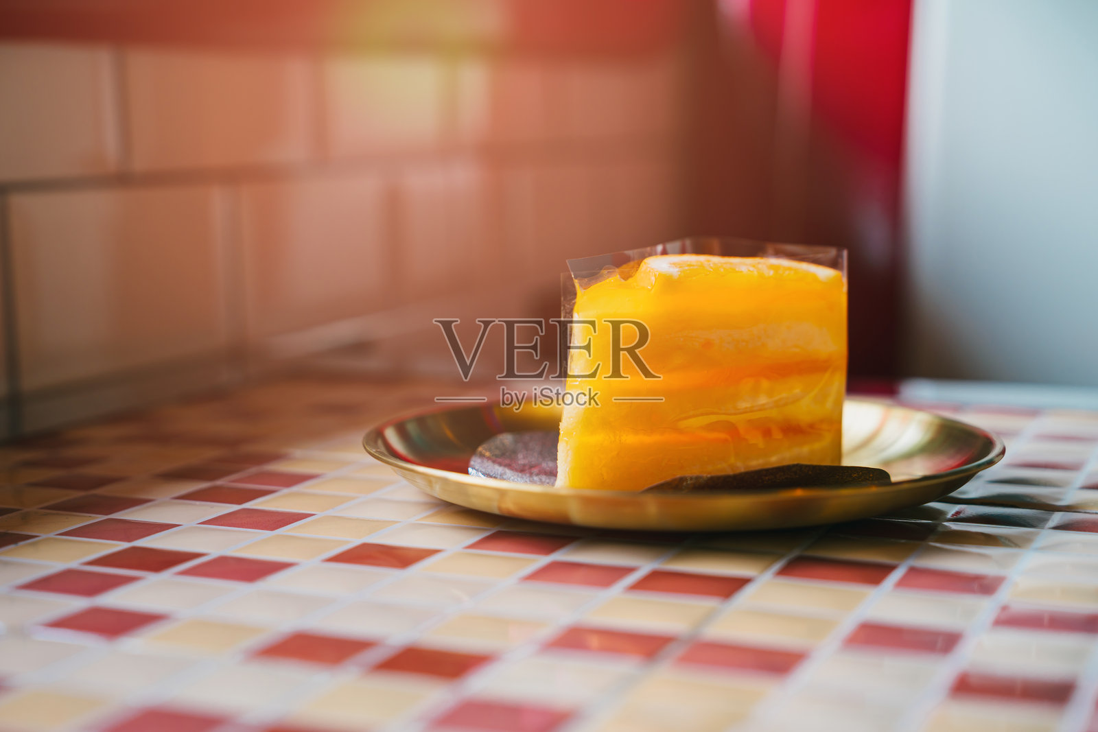 咖啡馆里的橙色蛋糕。分层柑橘甜点，配有饼干，放在装饰盘上，背景是色彩斑斓的马赛克瓷砖。照片摄影图片