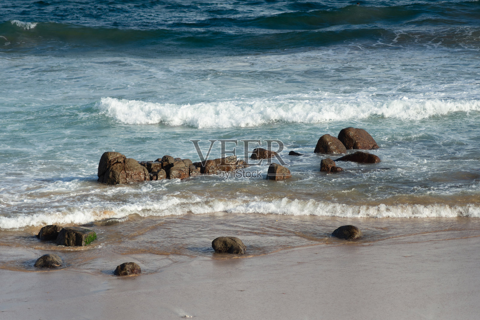美丽海滩的海岸上有黑色岩石。海浪拍打着沙滩，宛如天堂。照片摄影图片