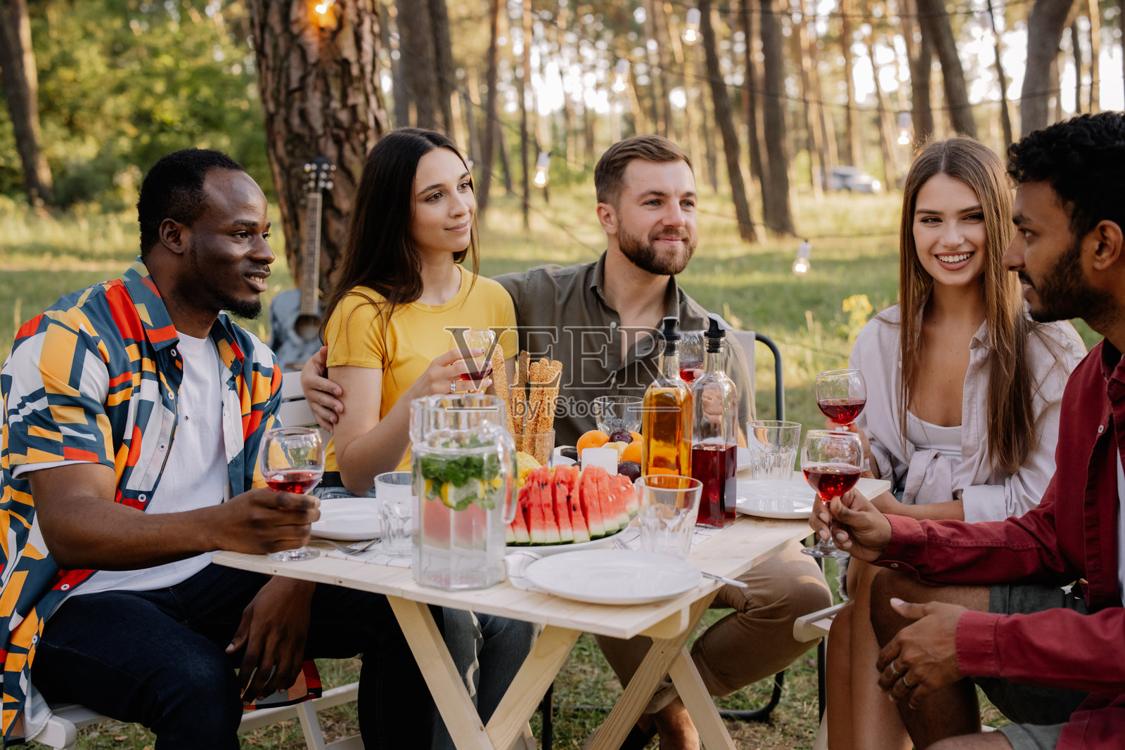 不同种族的朋友在森林中享受美酒和美食的野餐照片摄影图片