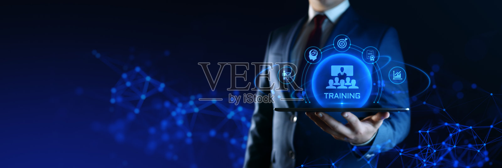 商人手持平板电脑，屏幕上显示培训图标。电子学习和在线教育概念照片摄影图片