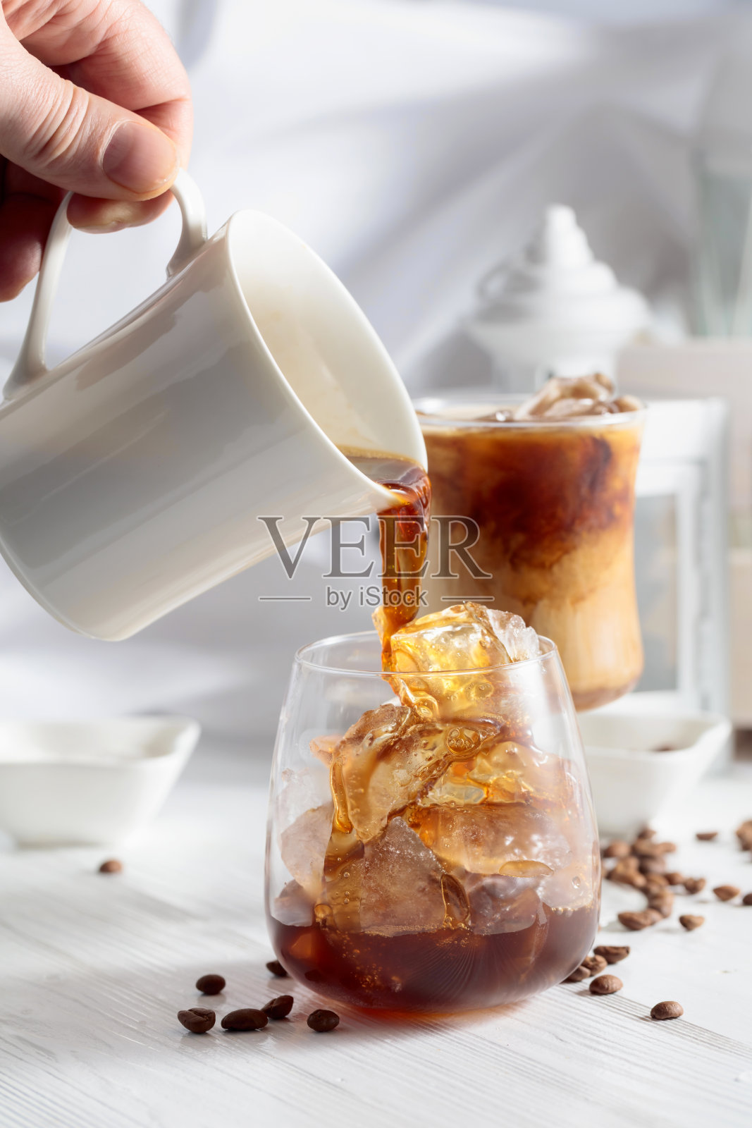 黑咖啡倒入装有冰块的玻璃杯中。照片摄影图片