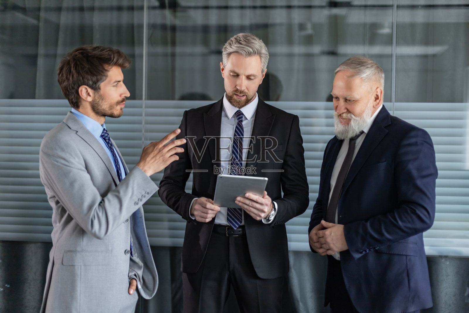 三位商务人士在现代办公室里一起使用平板电脑讨论工作照片摄影图片