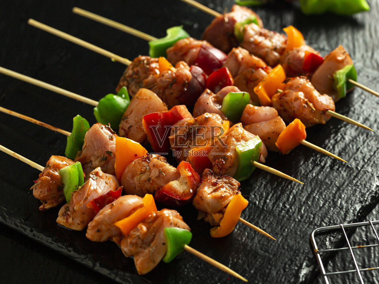 优质的香料烤鸡肉串，搭配烤制腌料，背景为黑色。照片摄影图片