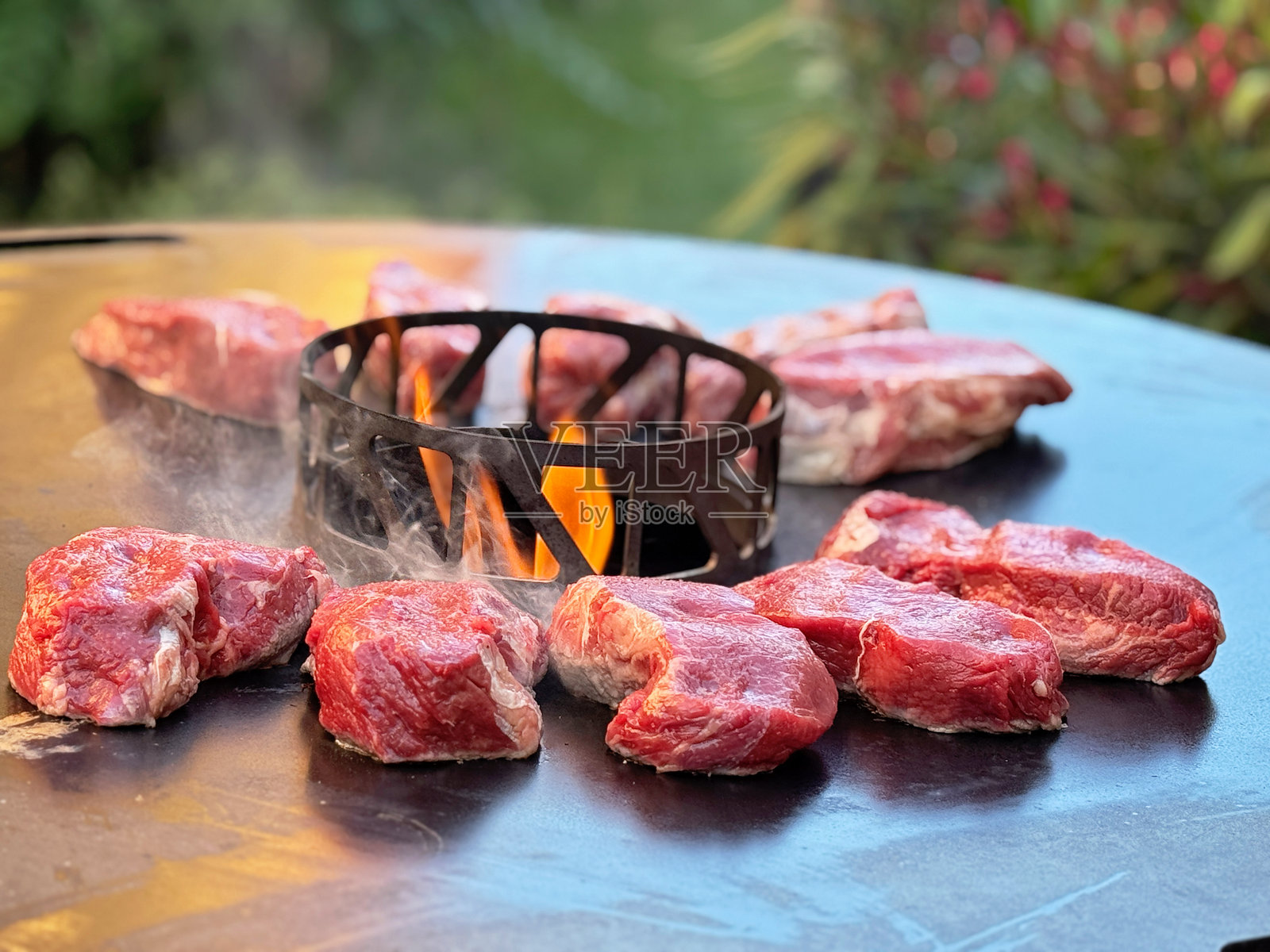 许多块多汁的牛排在烧烤架上滋滋作响。新鲜的肉在户外为夏季烧烤而烹饪。真实的生活，真实的人，食物准备和烧烤的概念。照片摄影图片