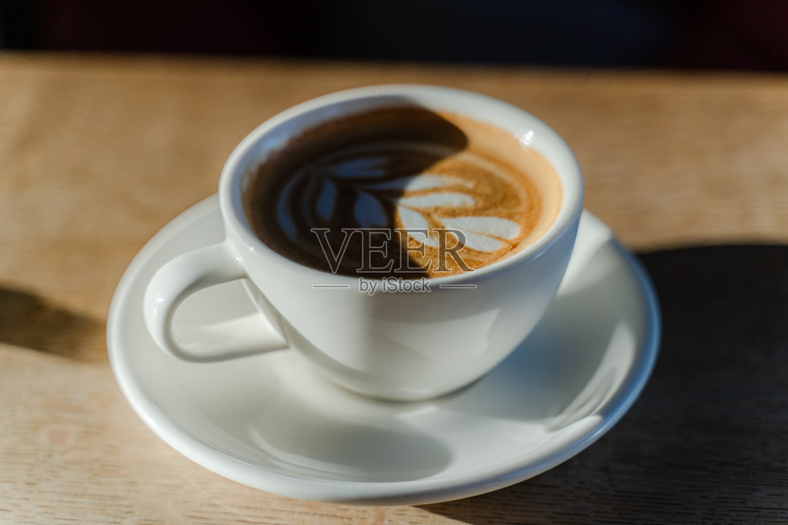 桌子上的白色杯子。卡布奇诺。泡沫上的图案。照片摄影图片