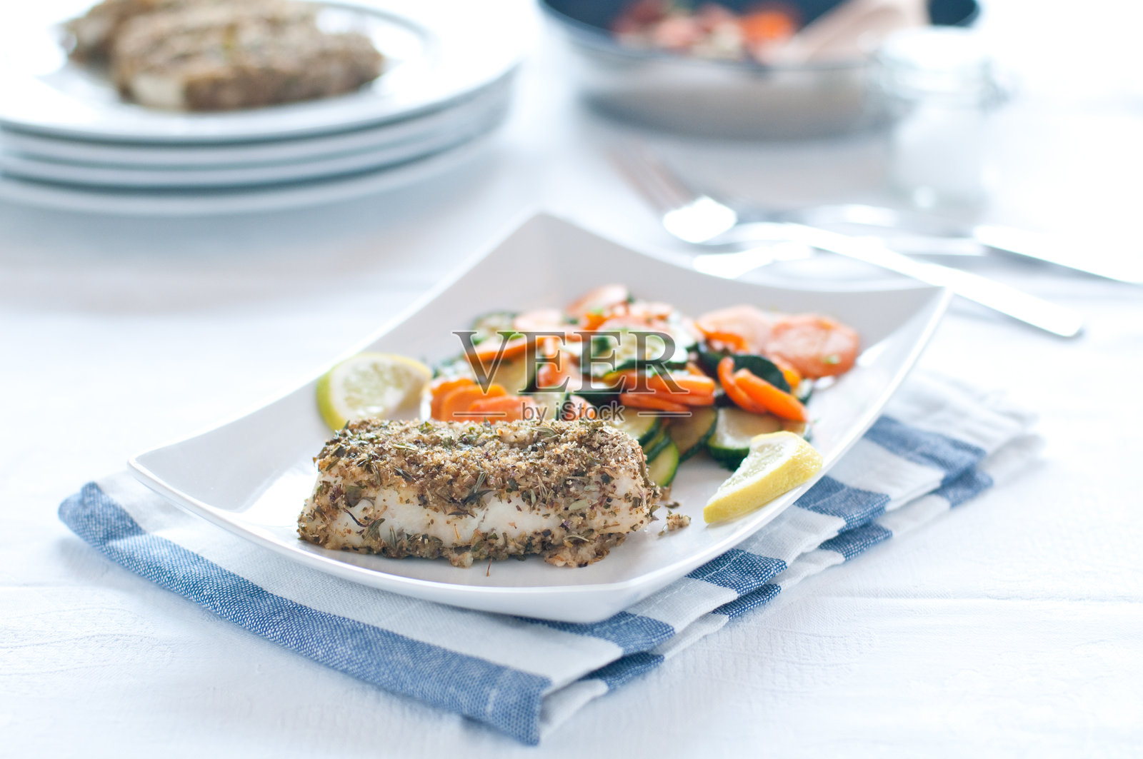 香辣面包裹的鳕鱼配胡萝卜和西葫芦照片摄影图片