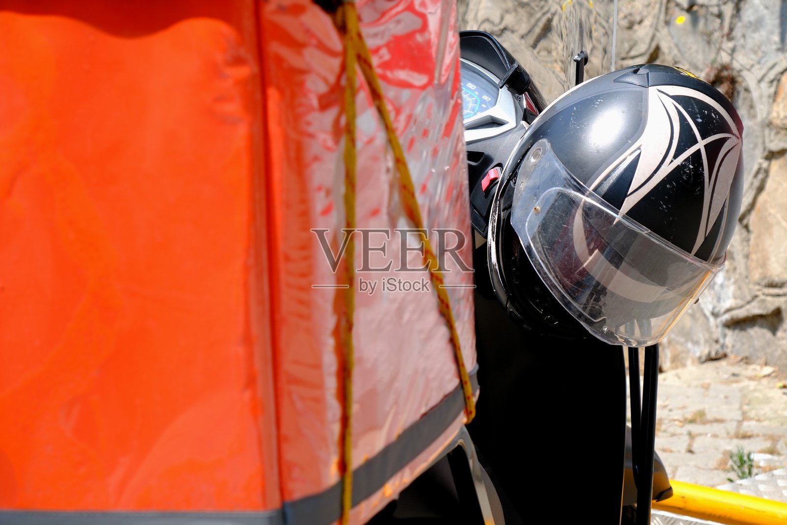 摩托车快递员将快速包裹送到家中，以及摩托车头盔的特写照片。照片摄影图片