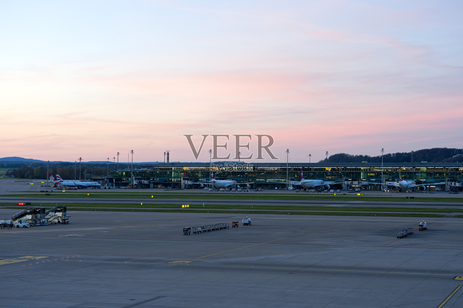 春季日落时分，瑞士苏黎世克洛滕机场中场停机坪上停放的客机美景。照片摄影图片